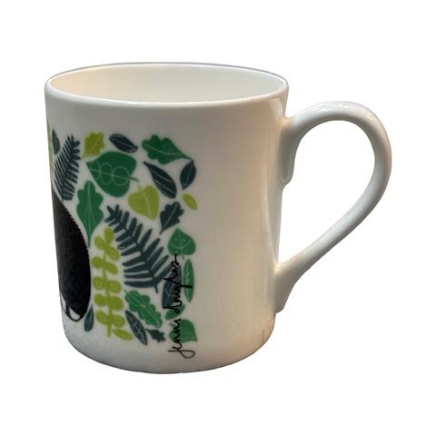 A white fine-bone china mug featuring an illustration of a black and white wildcat surrounded by green leaves.