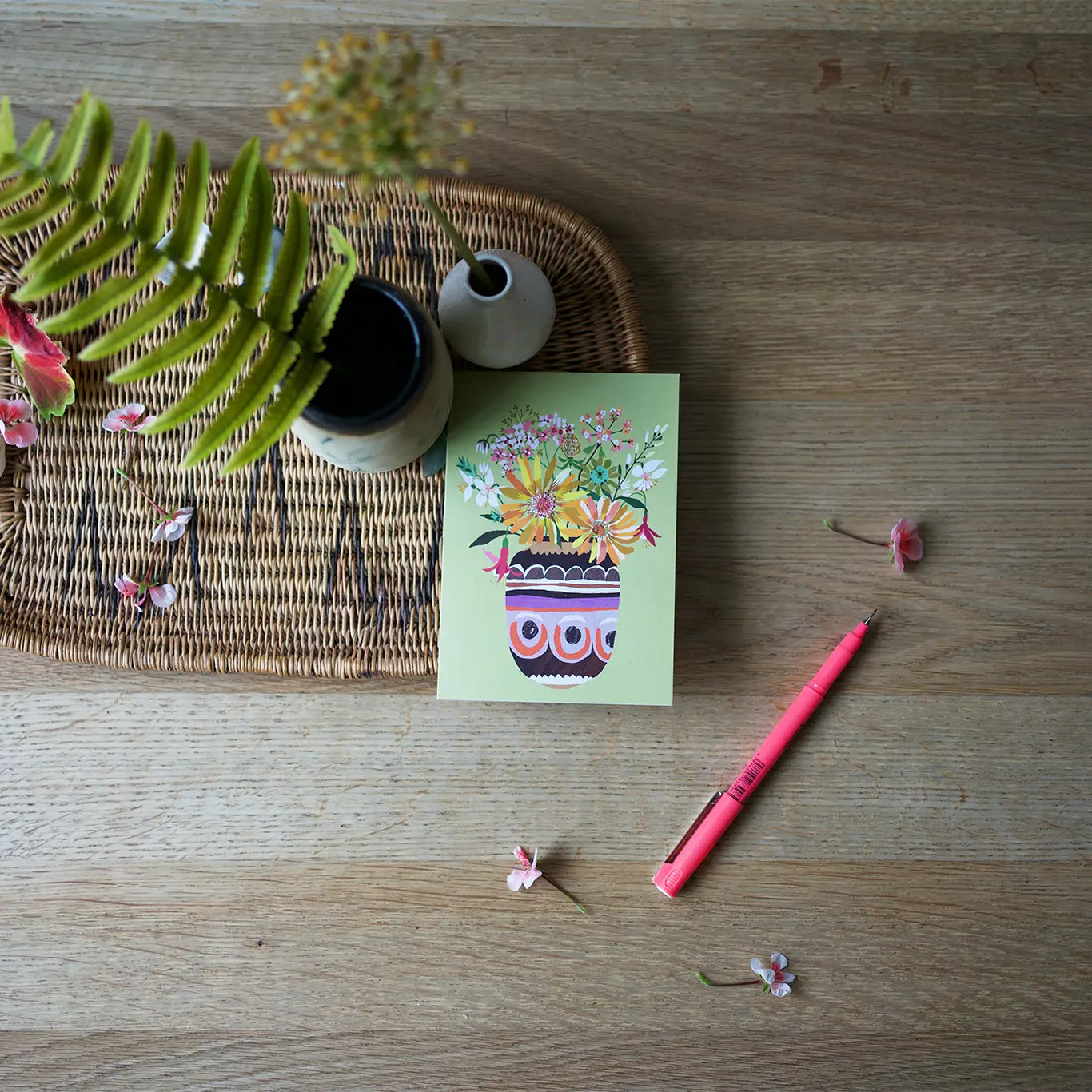Notebook with floral design, pen, and decorative items on a wooden surface.