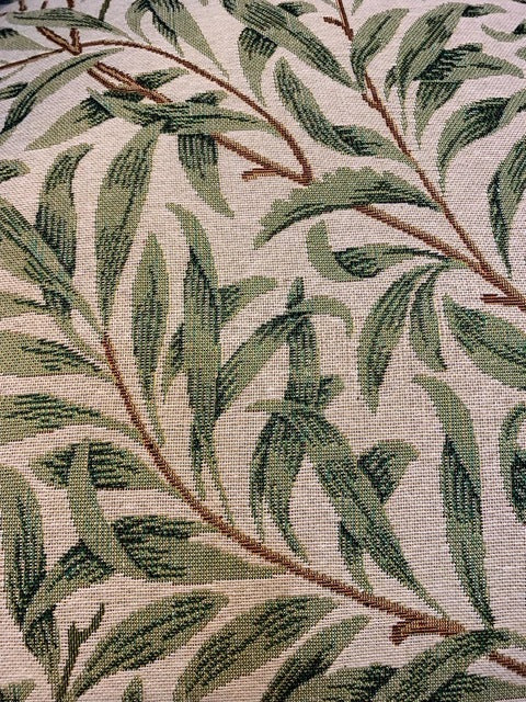 A William Morris style armchair with green leaf pattern on fabric, button-back design.