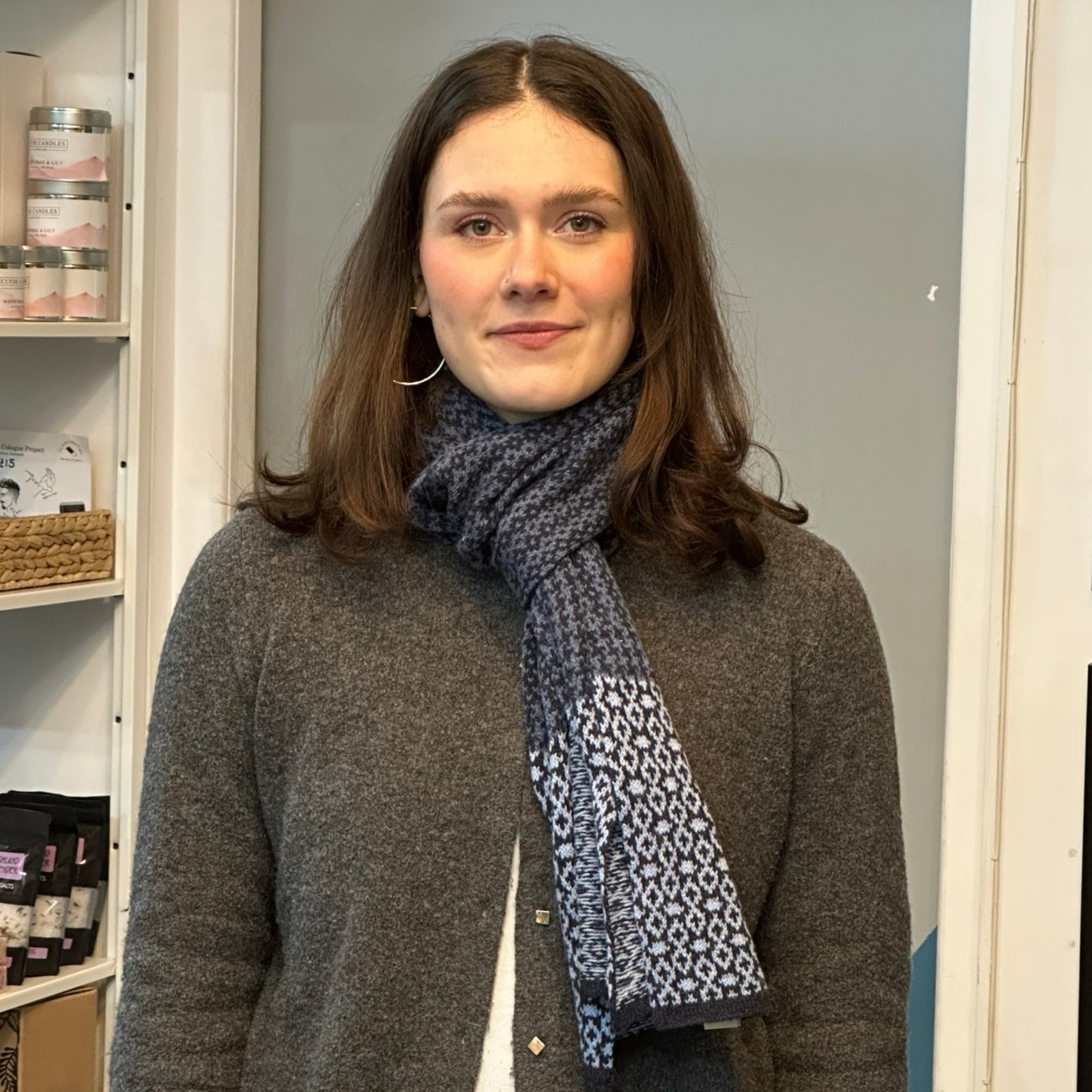A cosy and soft 100% lambswool knitted scarf with a denim blue, white and black geometric design.