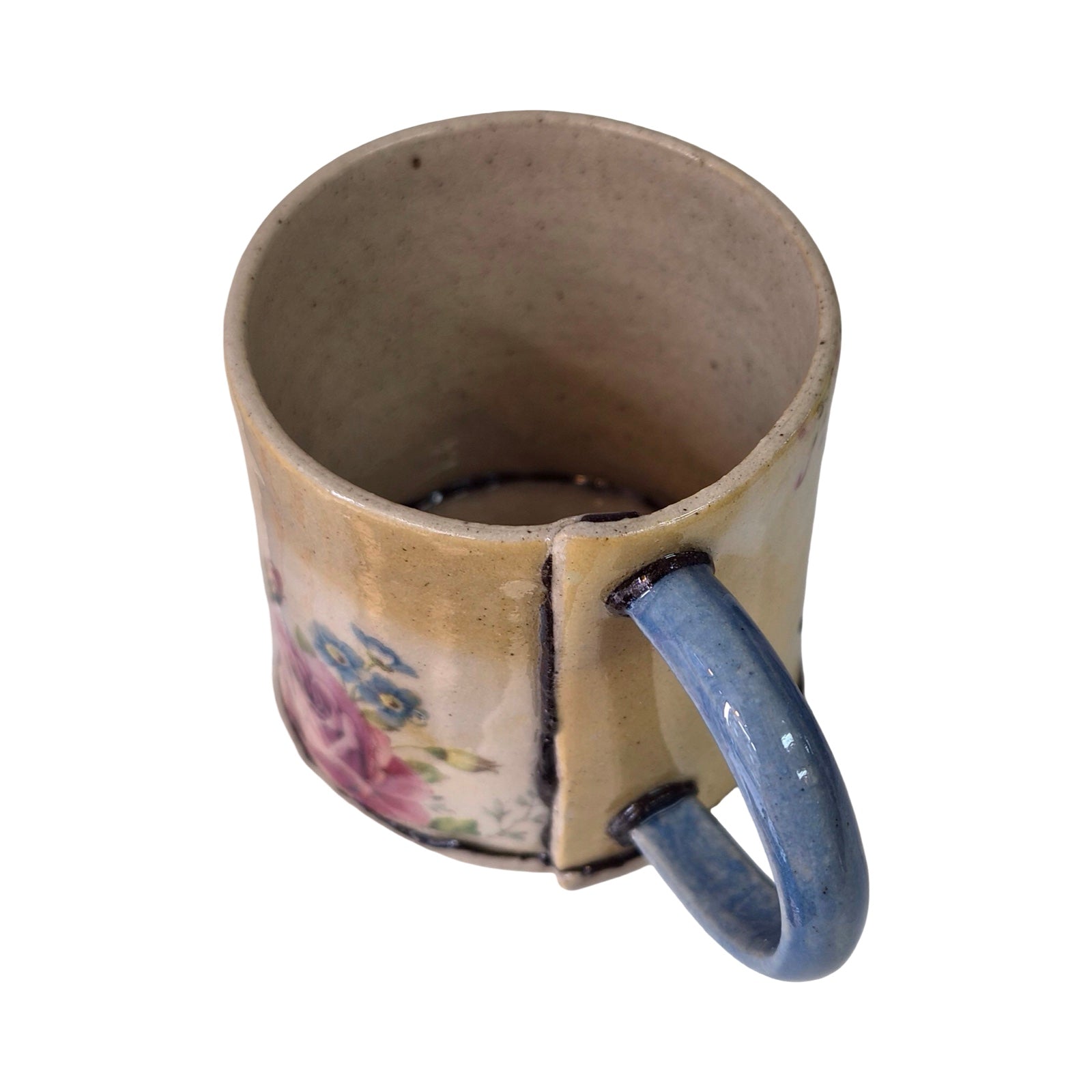 Ceramic mug with a blue handle on a white background.