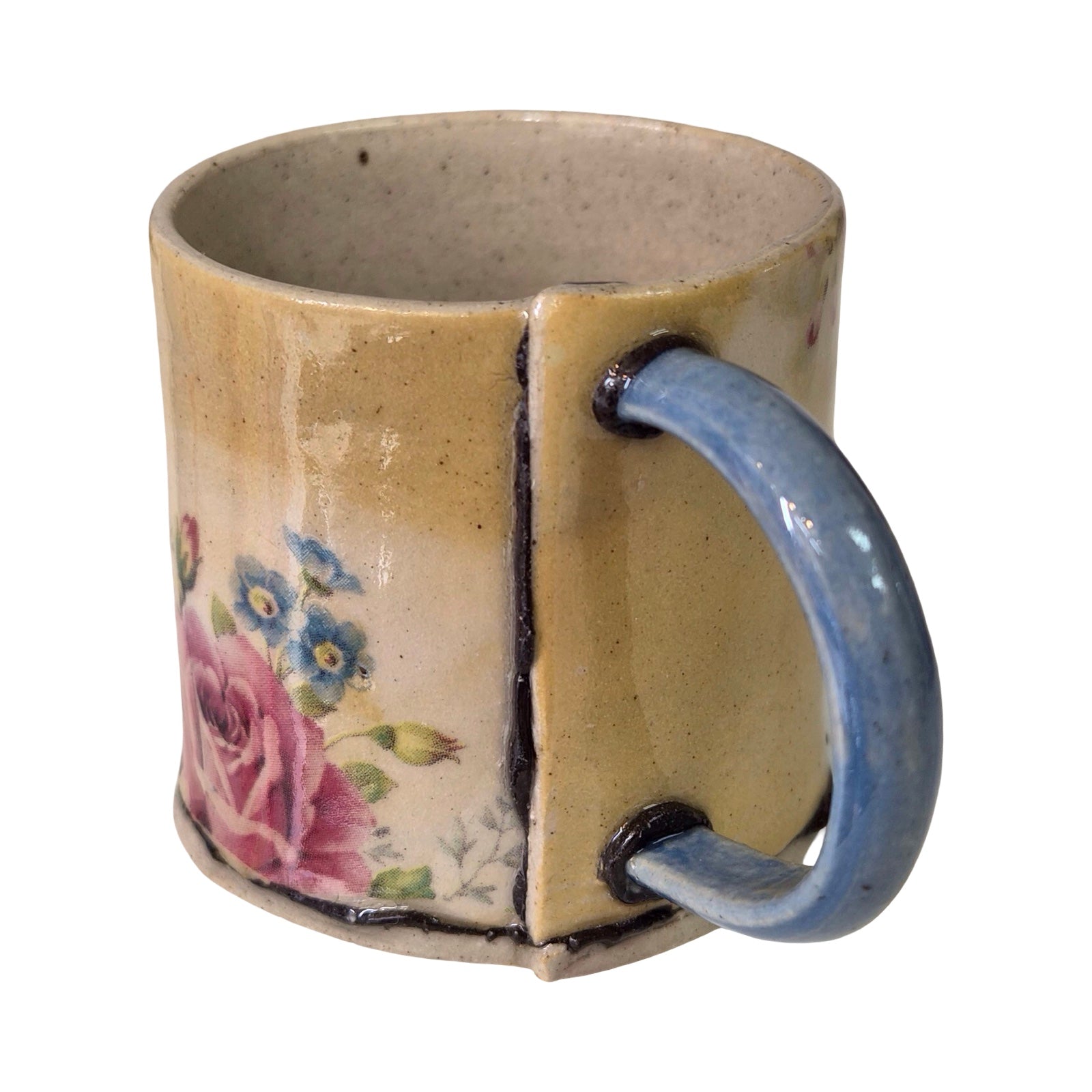 Ceramic mug with floral design and blue handle on a white background.