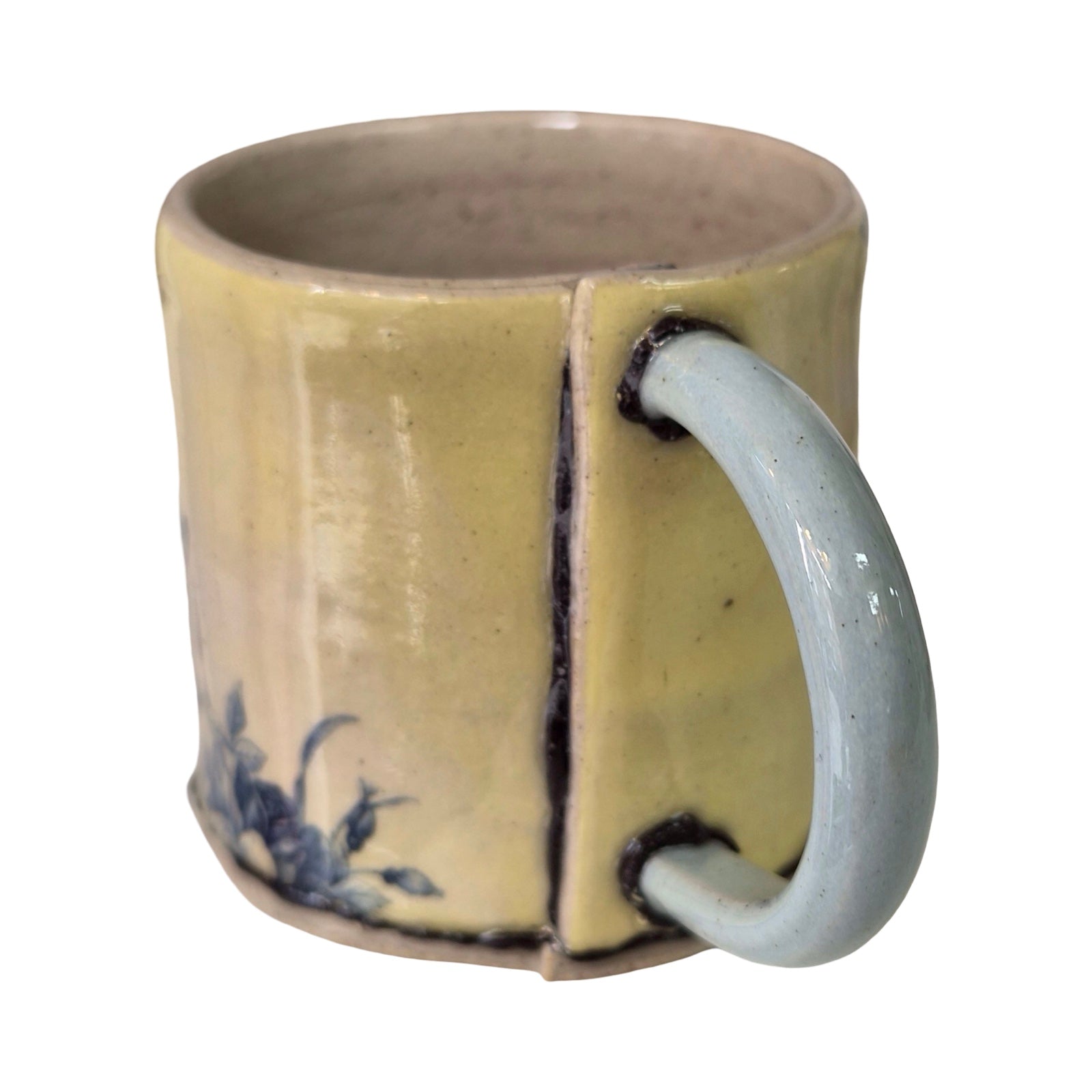 Ceramic mug with a light blue handle and blue floral design on a beige background.