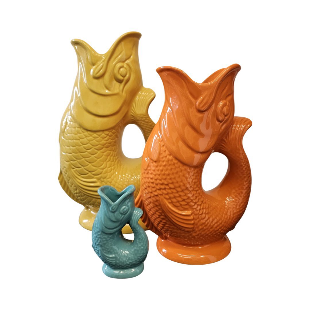 An extra large yellow fish shaped gluggle jug, a large orange fish shaped gluggle jug and a mini mint fish shaped gluggle jug.