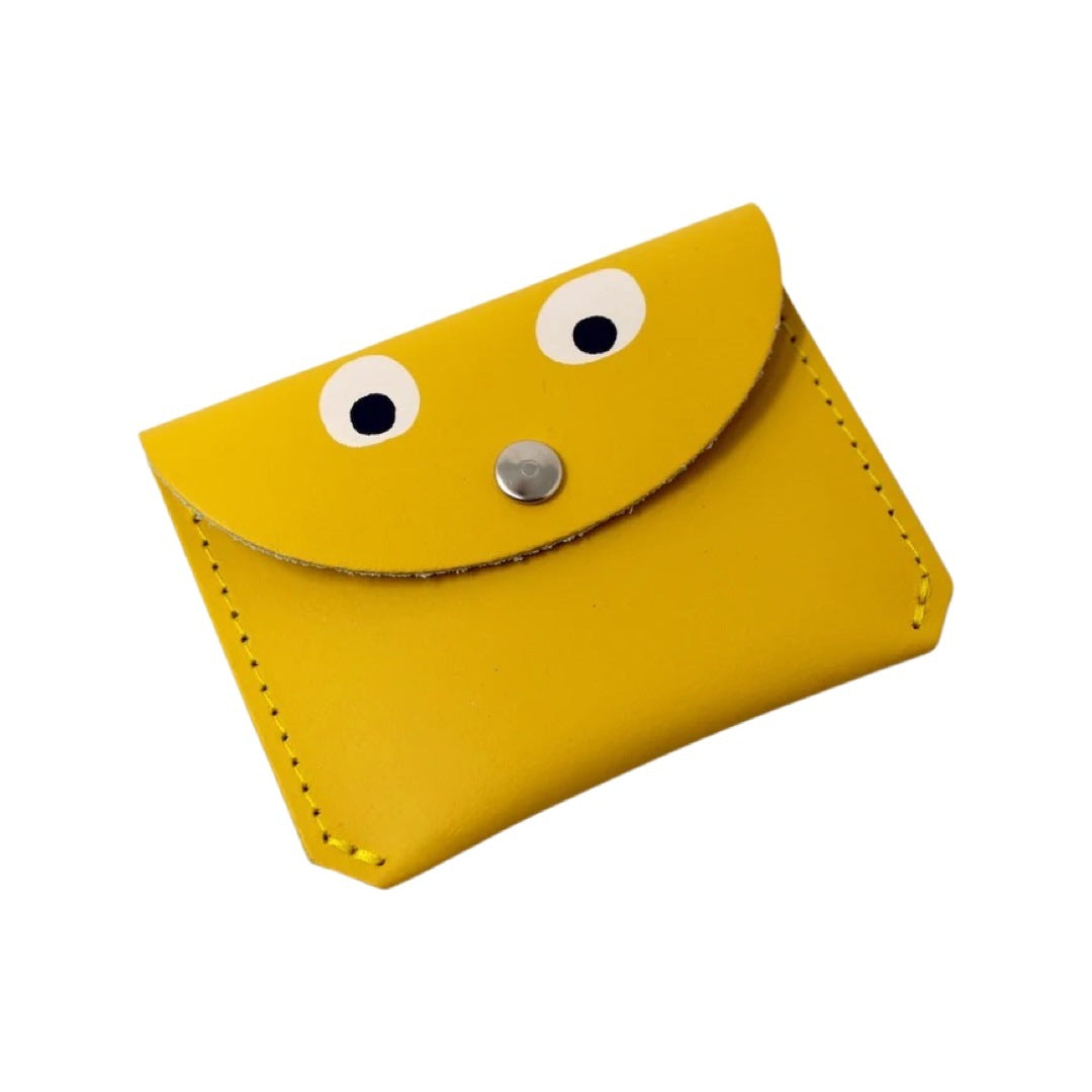 A yellow leather coin purse with googly eyes and a gold fastening in the centre.