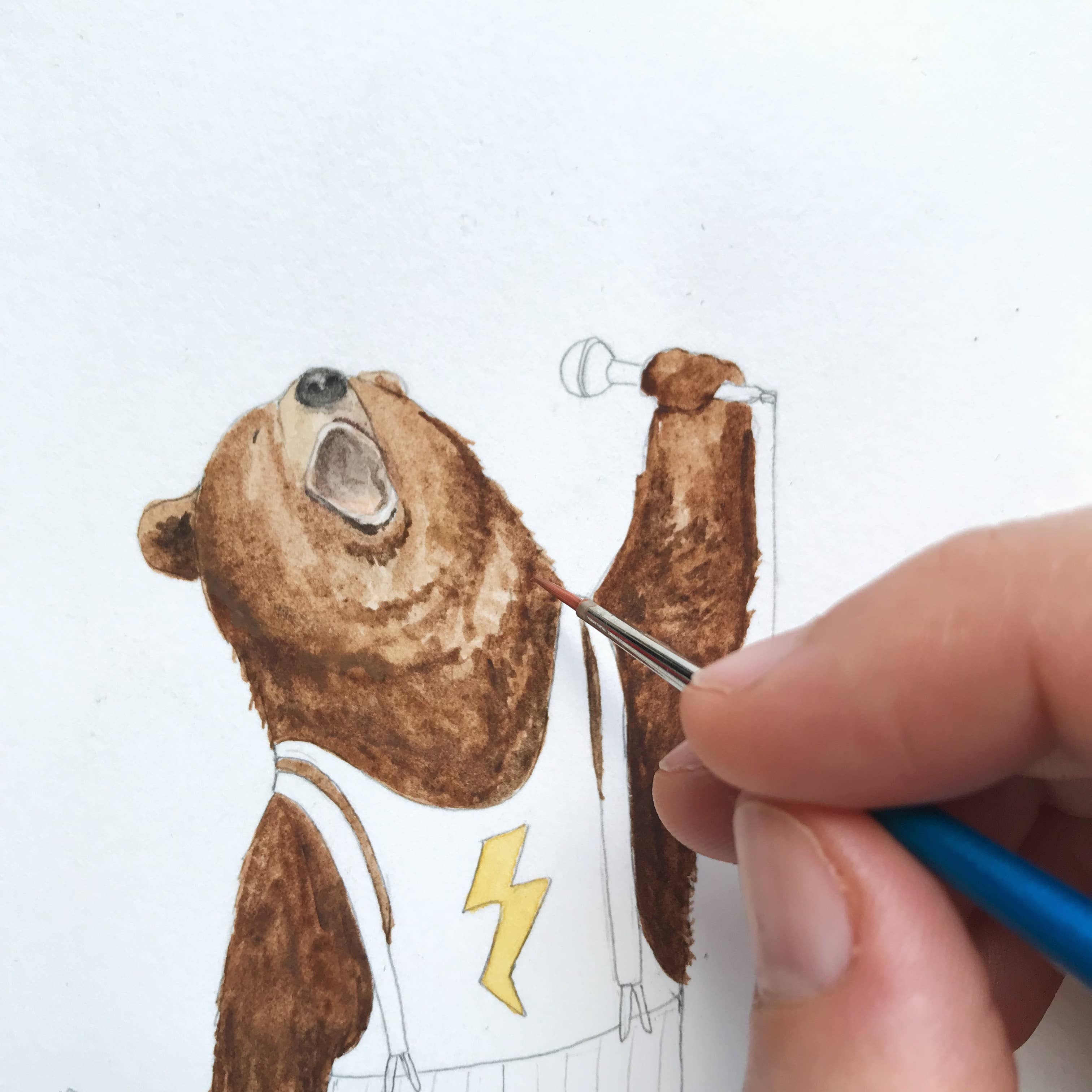 Hand painting a cartoon bear character on a white background.