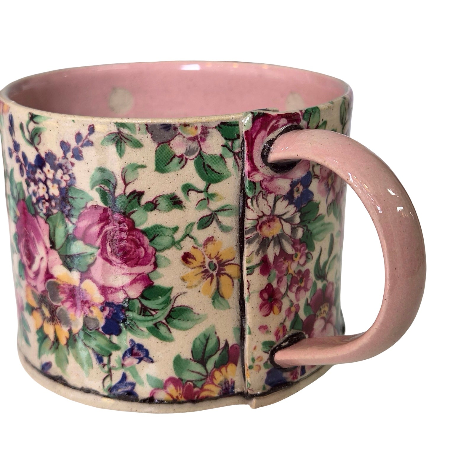 Floral-patterned mug with pink handle on a white background.