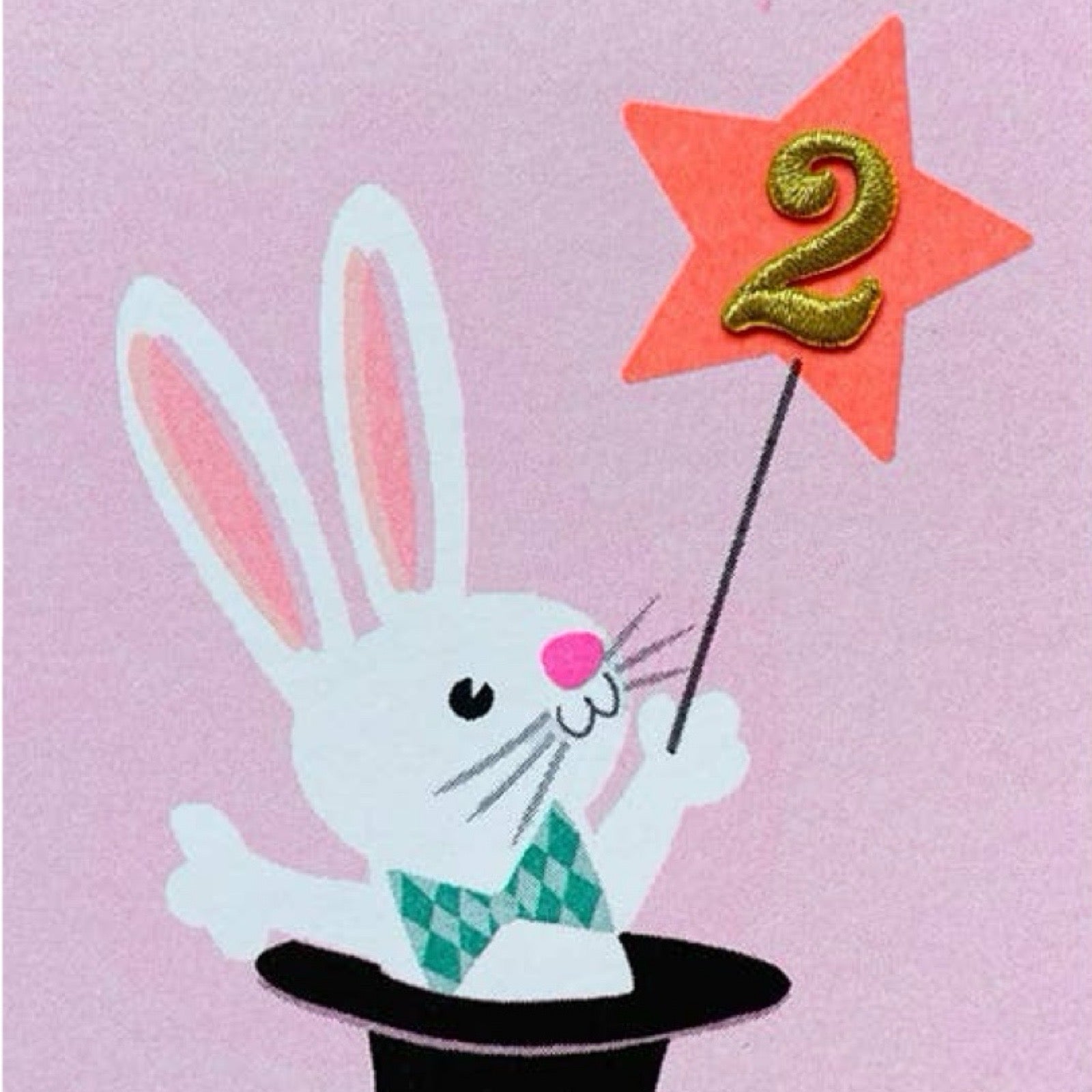 A pale pink birthday card with a white rabbit in a magician's hat, with a gold embroidered 2 in an orange star.