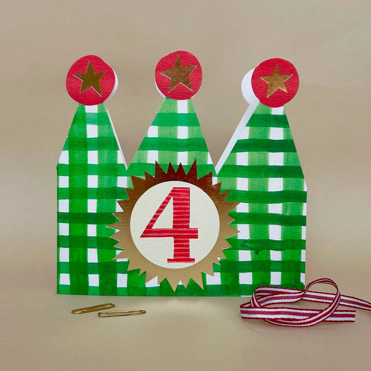 Decorative number '4' card with green checkered crown card on a beige background.