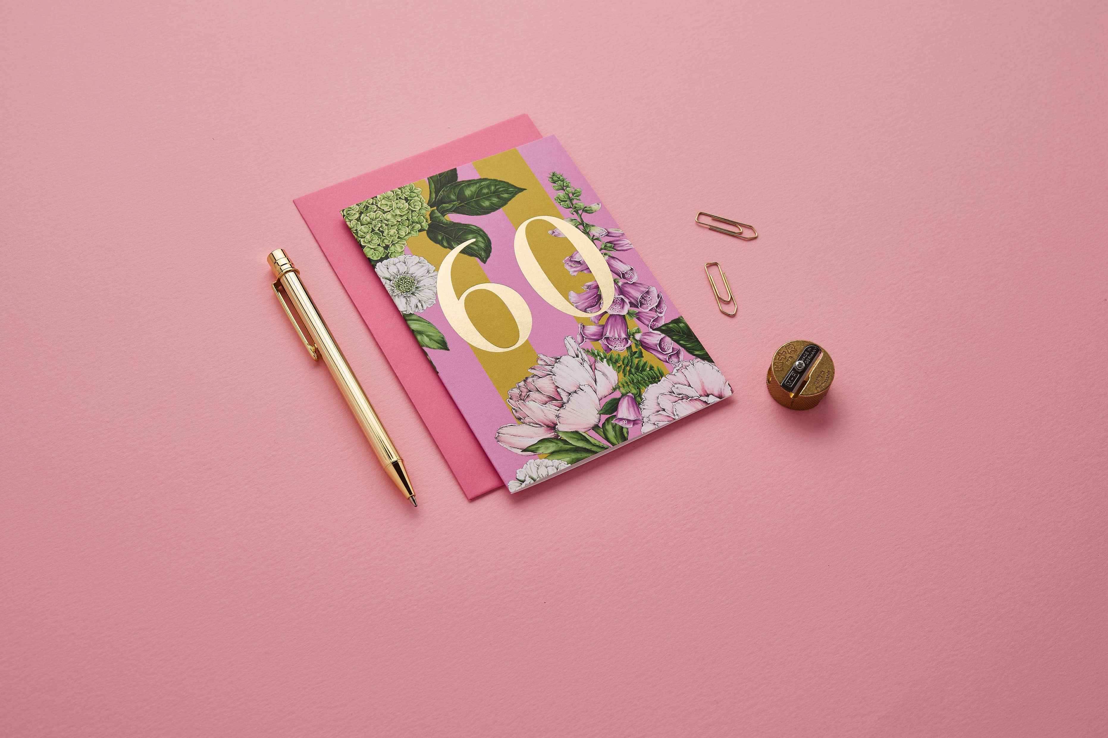 Notebook with floral design and number 60 on a pink background.