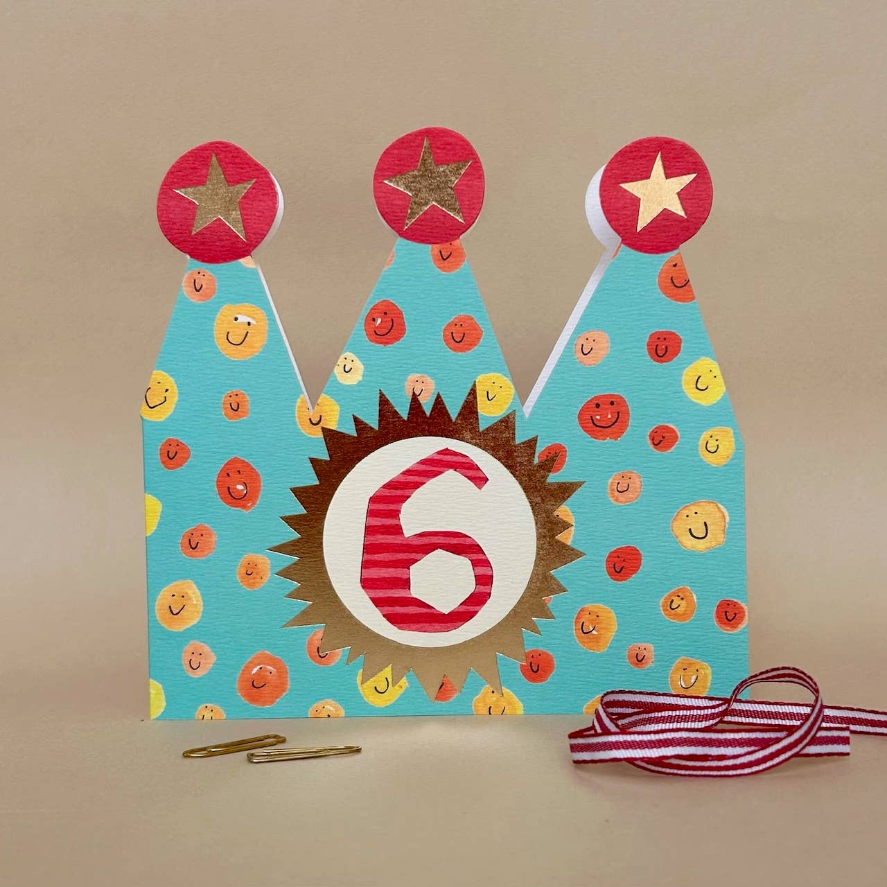 Colourful birthday hat with number 6 on a beige background.
