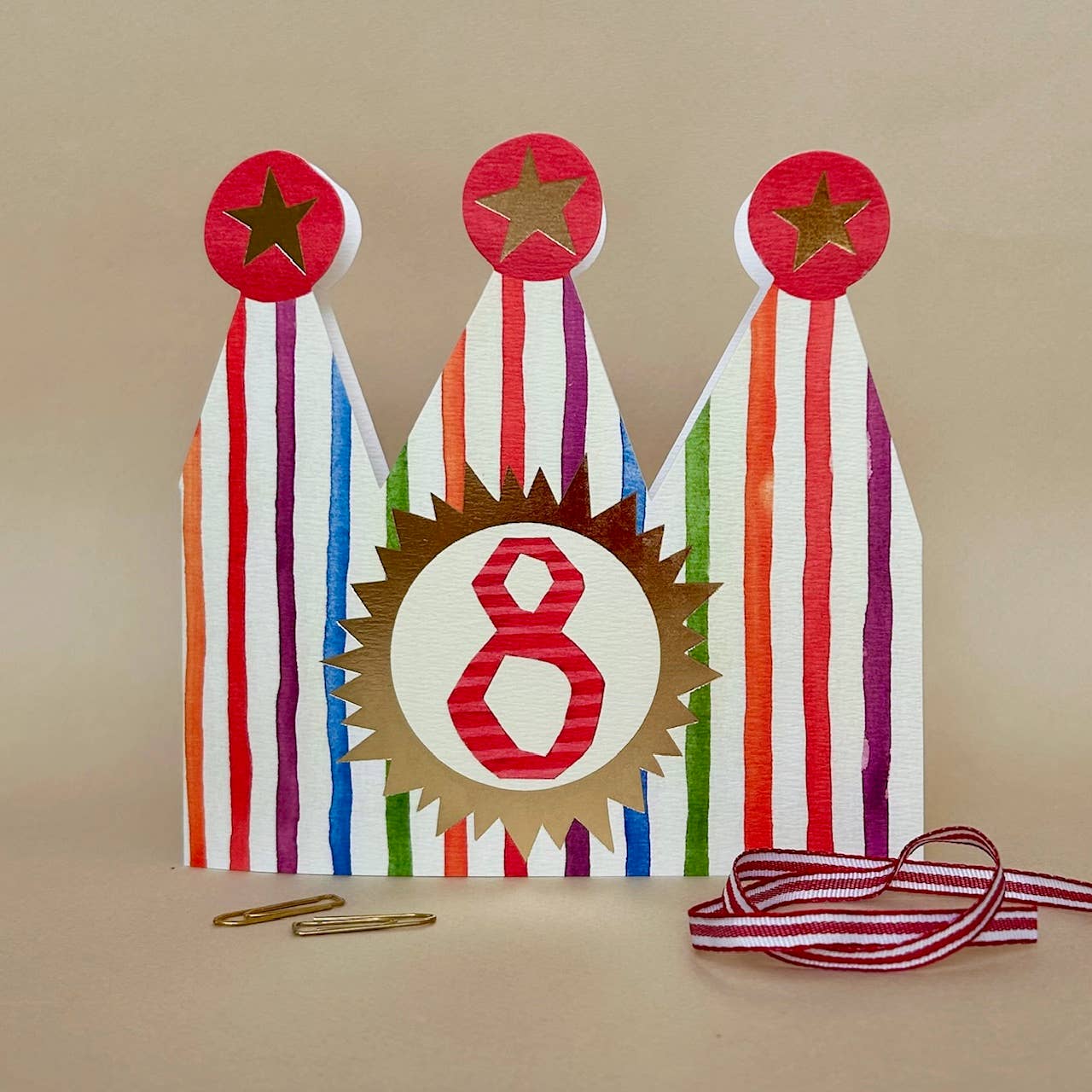 Decorative card with colourful ribbons and number 8 on a beige background.