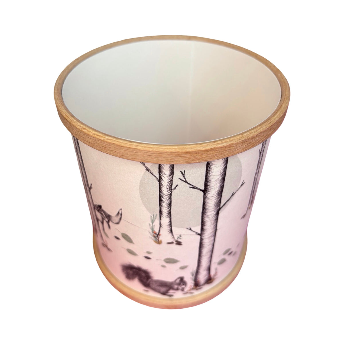 A cylindrical candle holder with a light wood rim and base, featuring a woodland illustration of a squirrel and fox among birch trees.