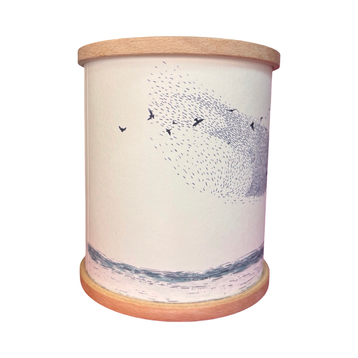 A cylindrical candle holder with a light wood rim and base, featuring an illustration of a murmuration of birds.