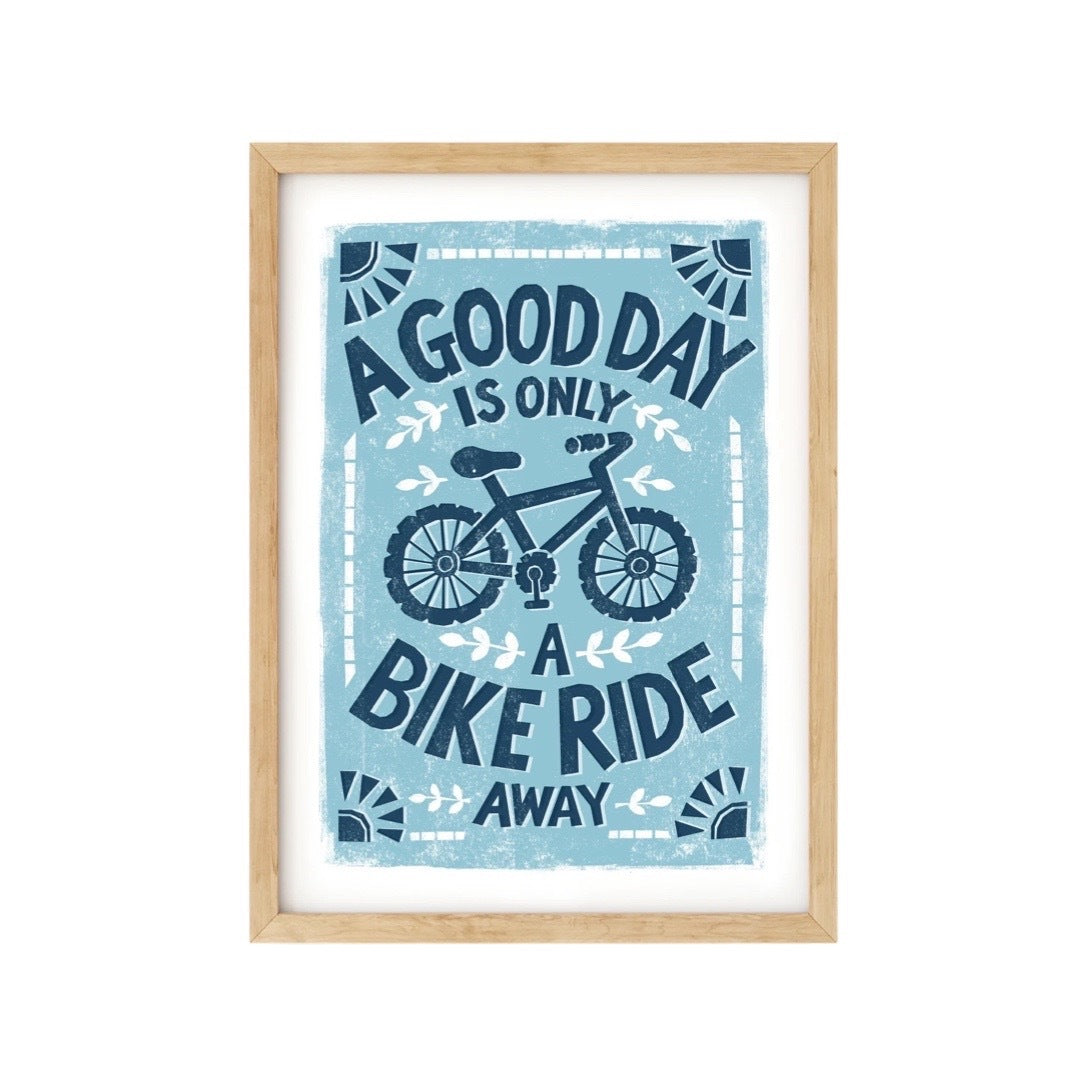 Cycling print featuring a illustration of a bicycle and the text a good day is only a bike ride away in blue against a pale blue background.