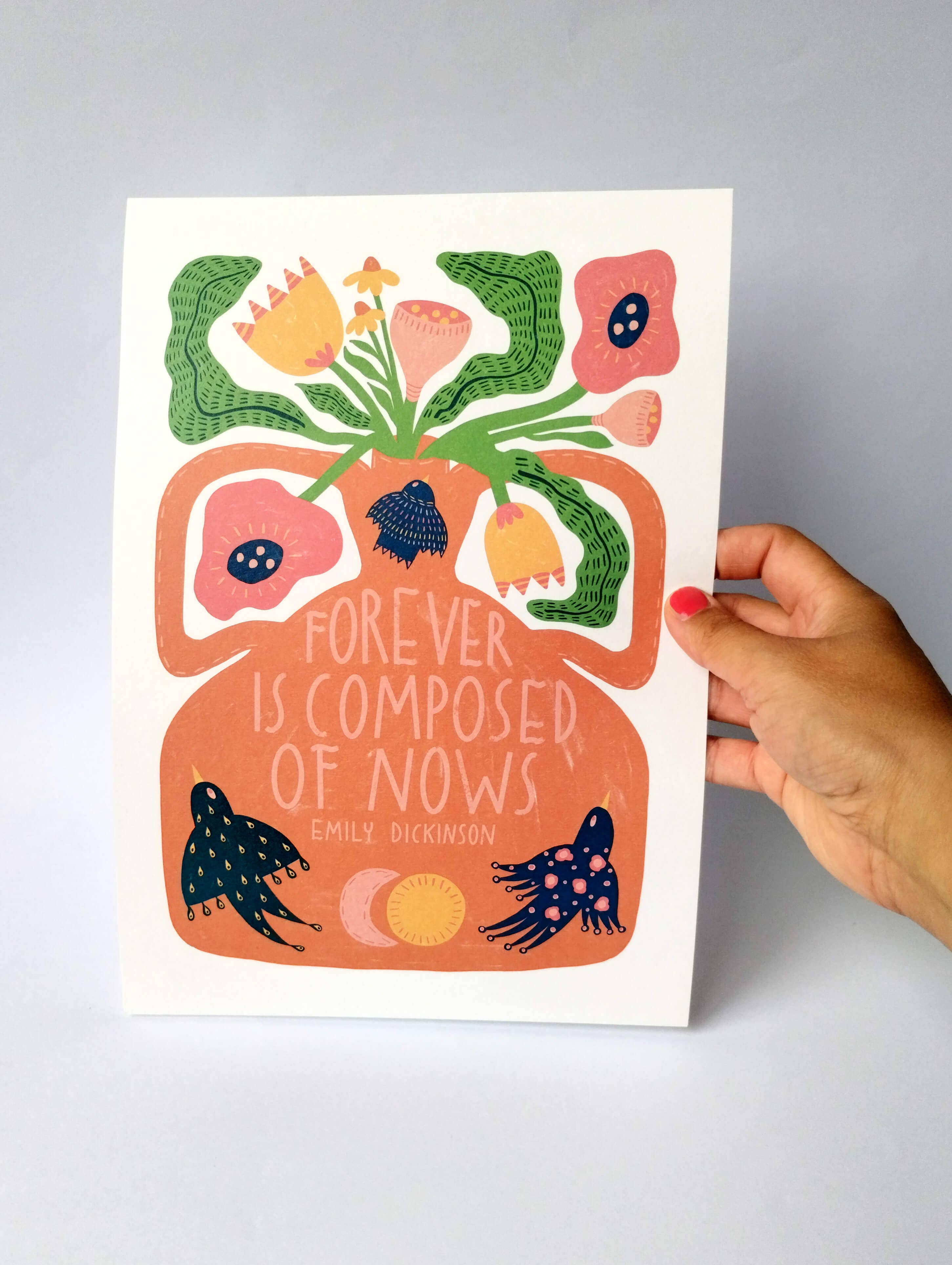 Hand holding a colourful poster with floral design and text against a grey background.