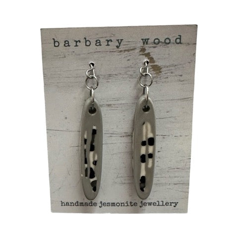 A pair of long thin oval shaped earrings in grey with a black and white abstract design and silver earring hooks.