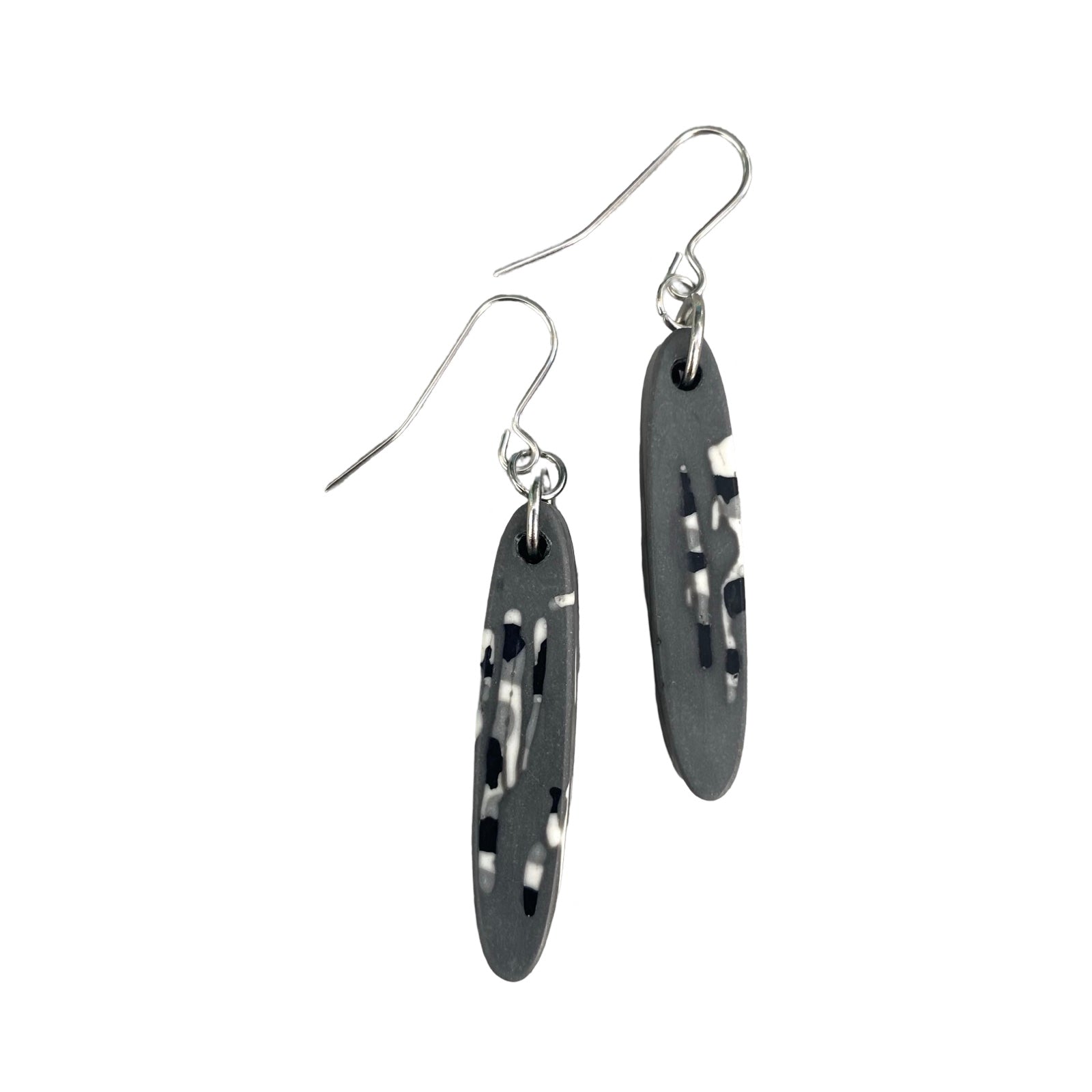 A pair of long thin oval shaped earrings in grey with a black and white abstract design and silver earring hooks.