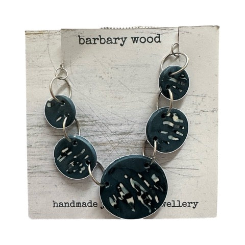 Necklace with 5 blue circular pendants with black and white abstract designs held together with silver findings.