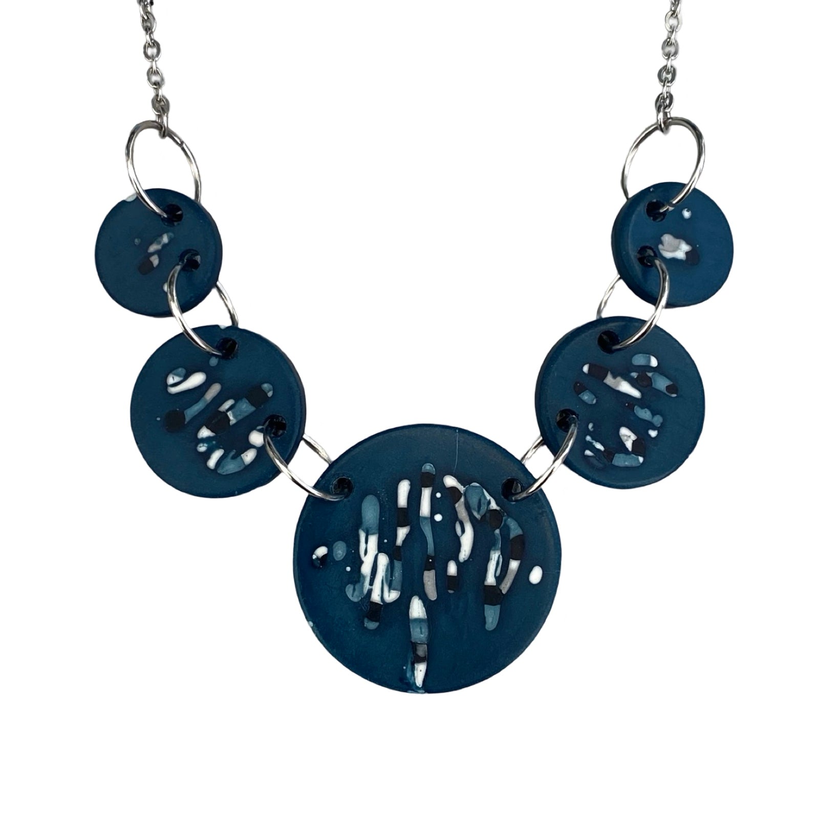 Necklace with 5 blue circular pendants with black and white abstract designs held together with silver findings.