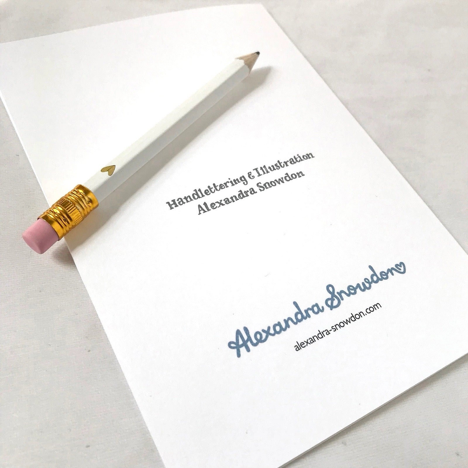 Pencil on the back of a card with text and a website URL.