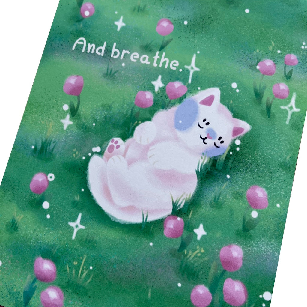 Art print of a white cat sleeping amongst pink tulips in a field. The text reads 'And breathe'.