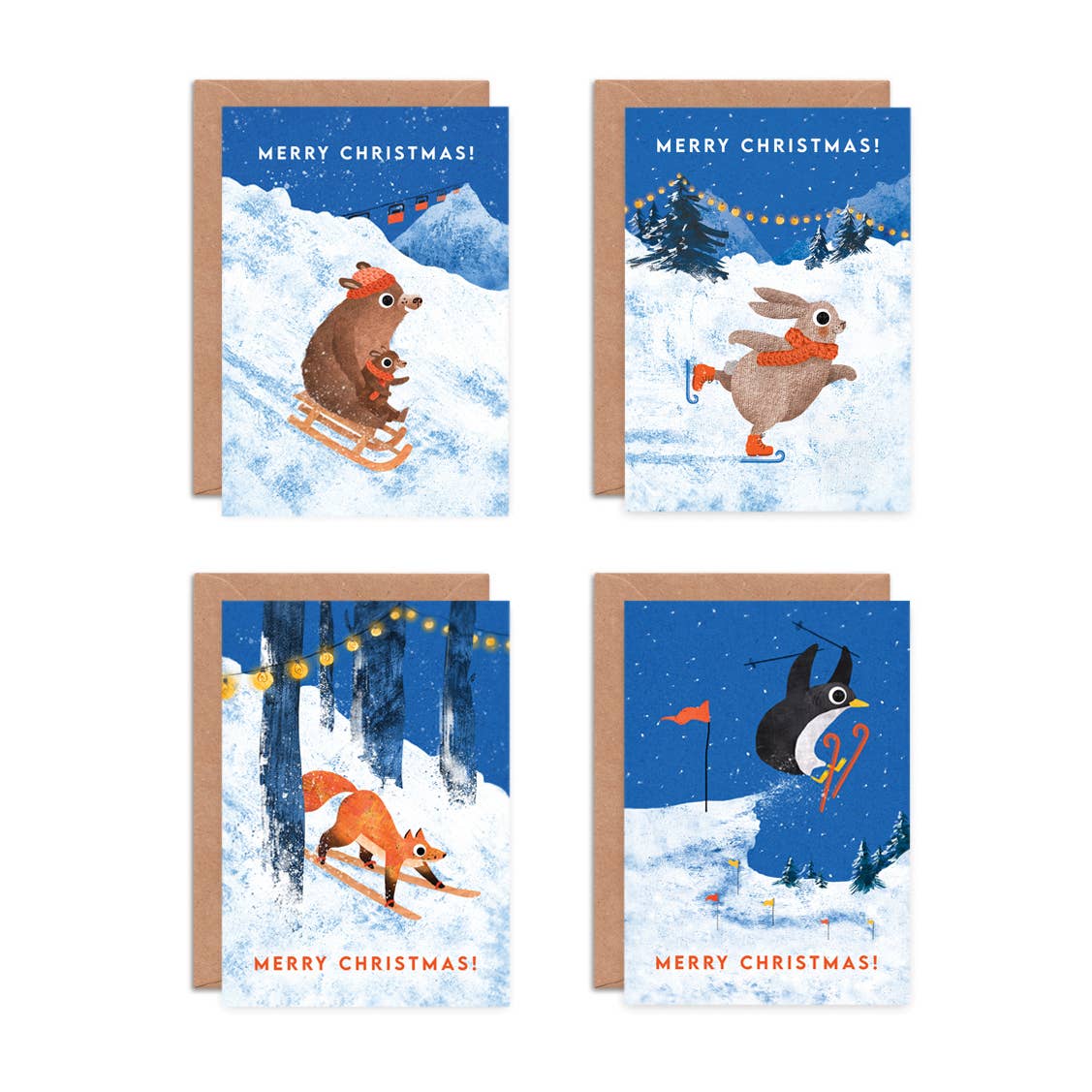 Four Christmas greeting cards arranged in a grid on a white background, each with a kraft envelope behind it. The card designs show winter animals in snowy scenes: a mole and baby mole sledging, a rabbit ice skating, a fox snowboarding, and a penguin skiing.