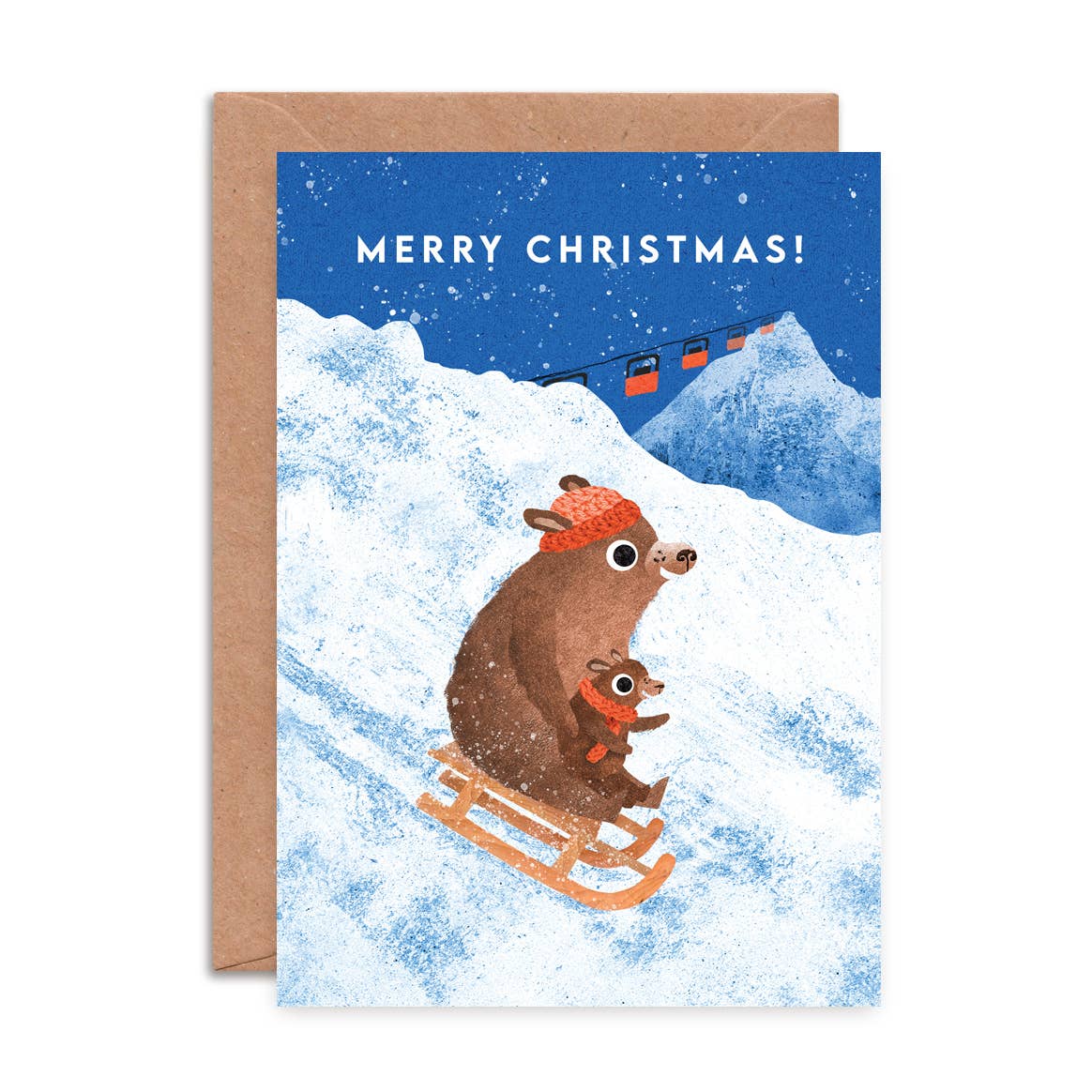 A Christmas greeting card with a kraft envelope, featuring an illustration of a brown mole and a small mole sledding down snowy mountains under a blue sky with the text 'MERRY CHRISTMAS!'.