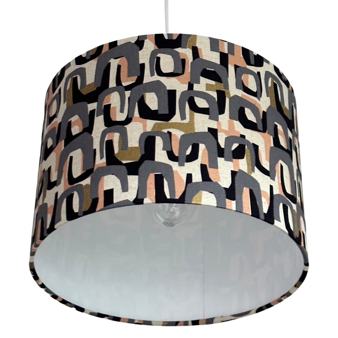 lampshade with a grey, peach, black and gold arch pattern.