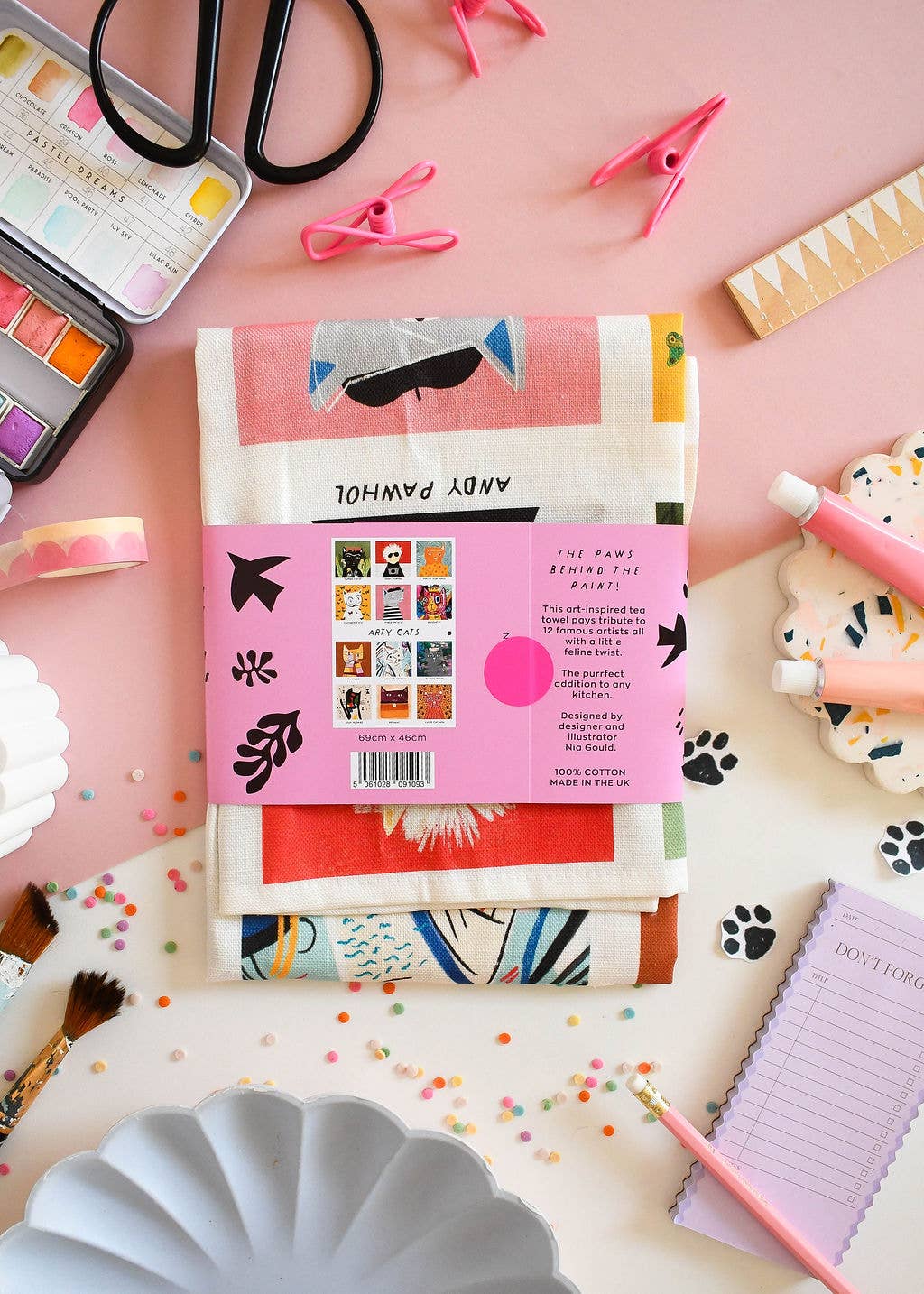 Colourful stationery items including a pink package with a label on a pink background.