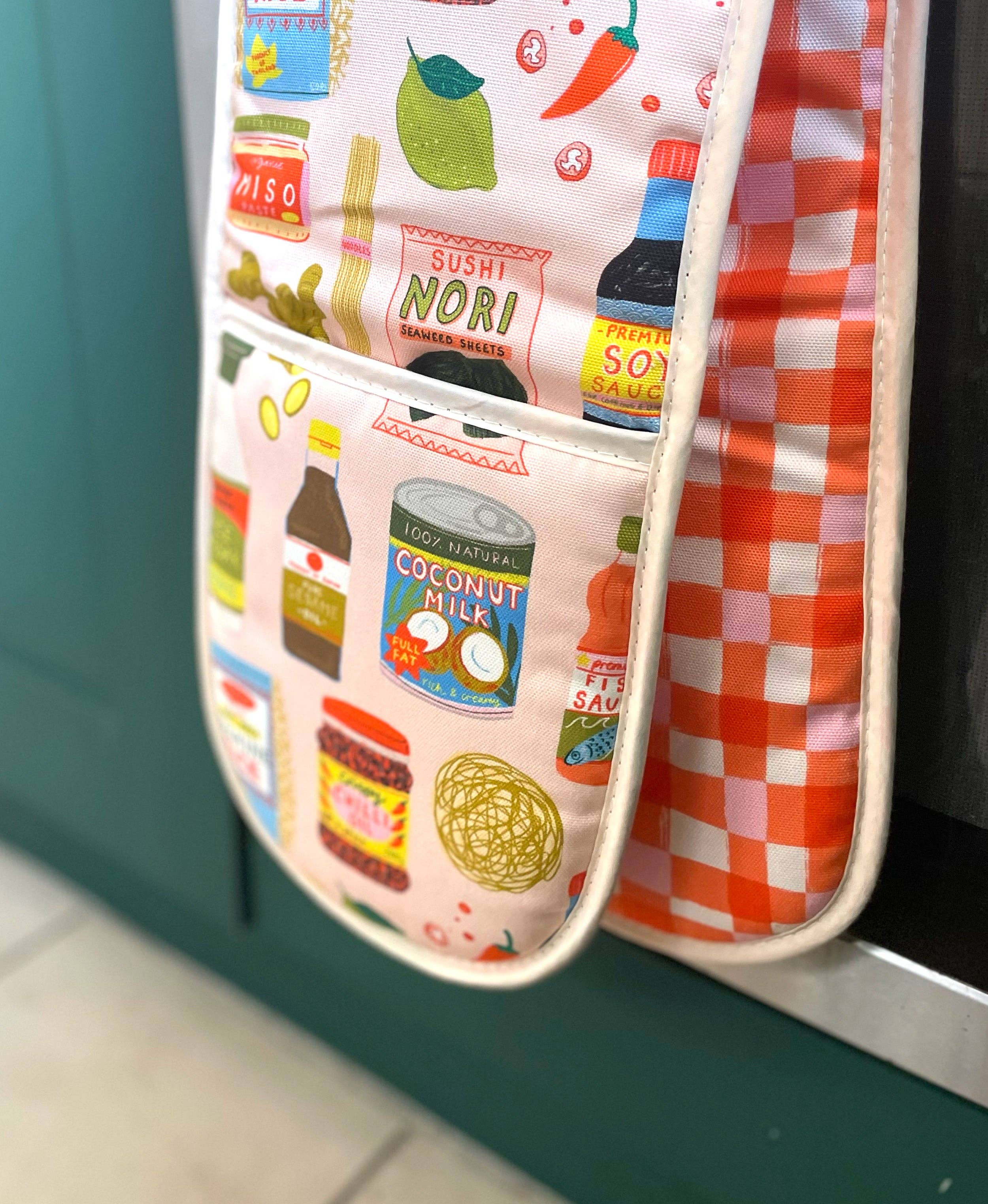 Oven mitt with food-themed design hanging on a green wall.