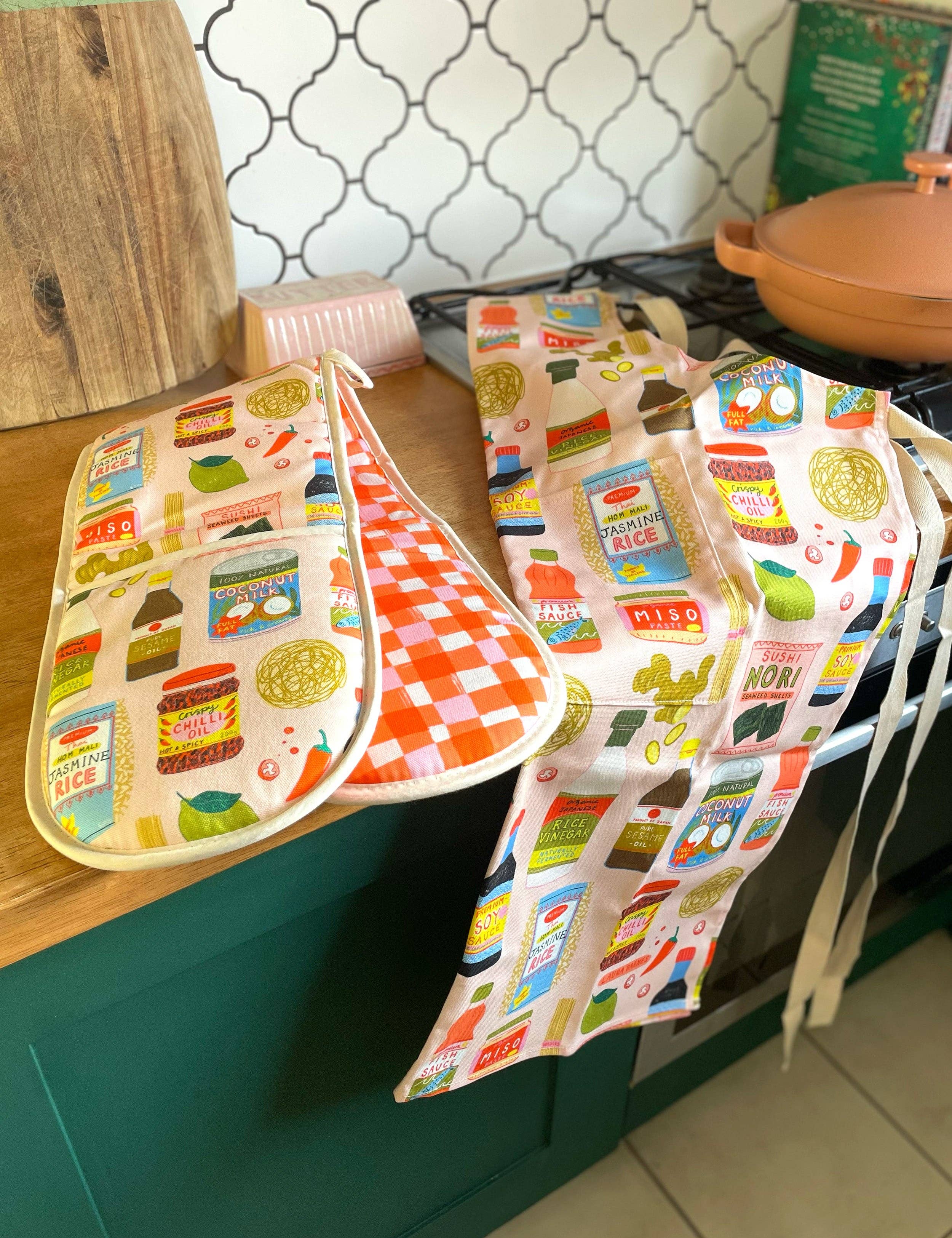 Colorful aprons with vintage-style food packaging designs hanging on a kitchen counter.