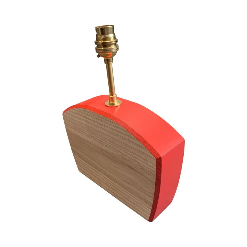 The side of shaped wooden lamp base with red edging.