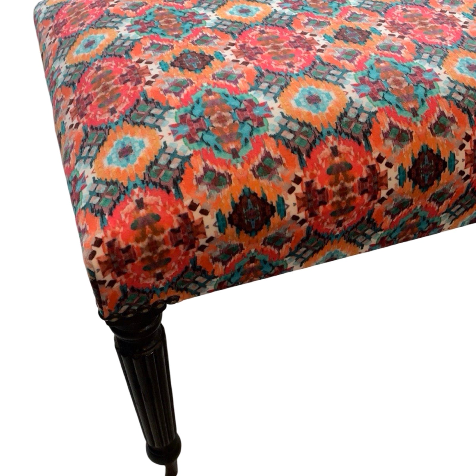 Multicolored patterned fabric on bench with a leg a white background.