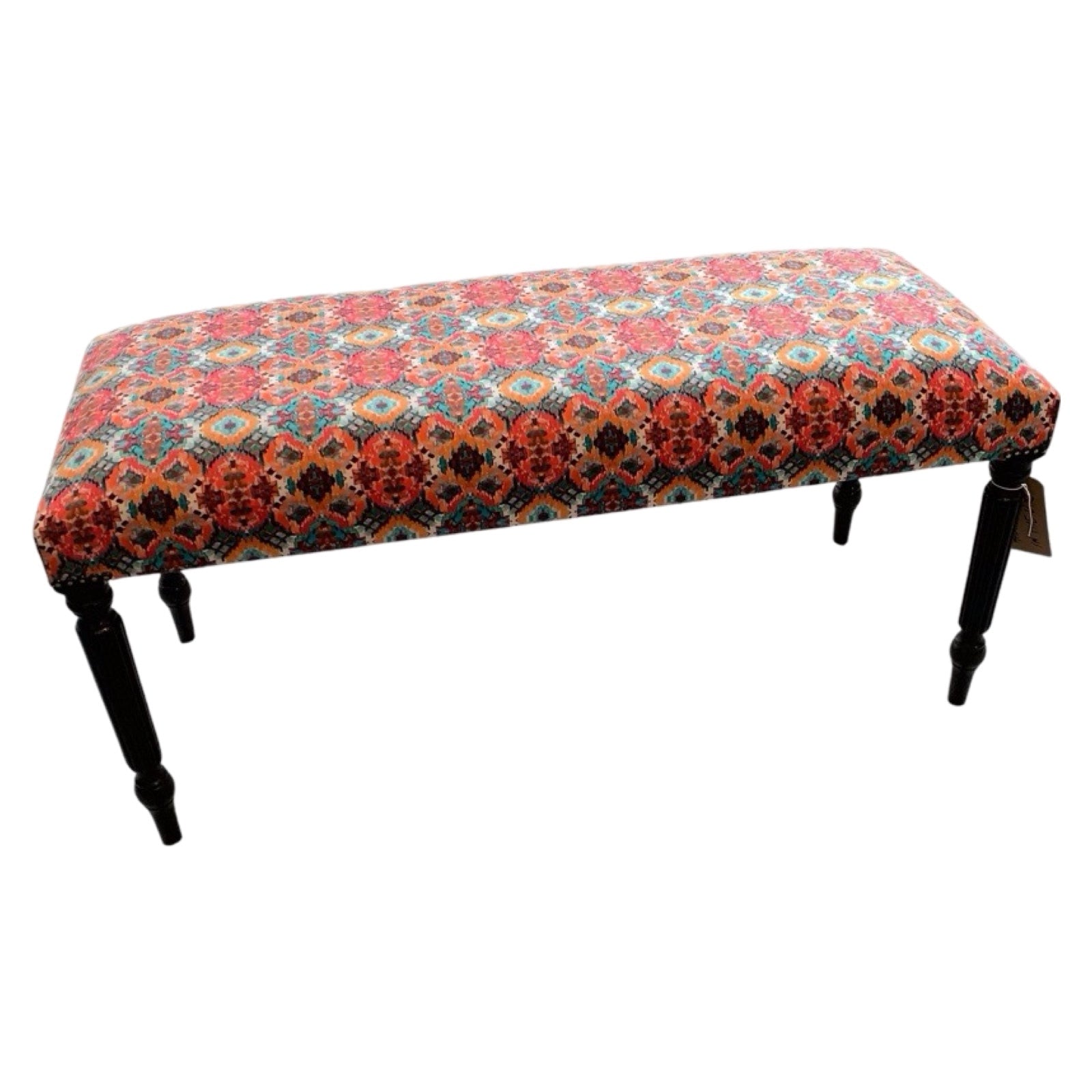 A rectangular bench with multicolored velvet upholstery, metal studs, and black wooden legs.