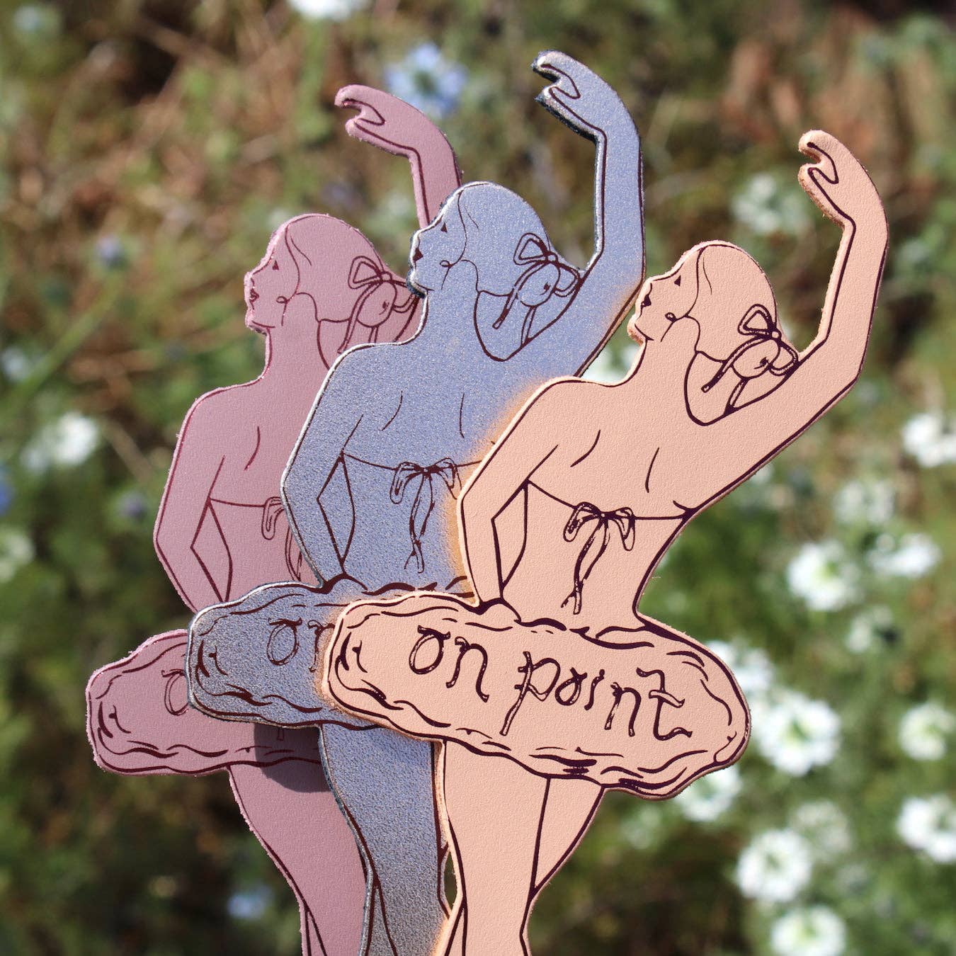 Three bookmarks of ballet dancers with a 'on point' text on the tutu's against a blurred trees background.
