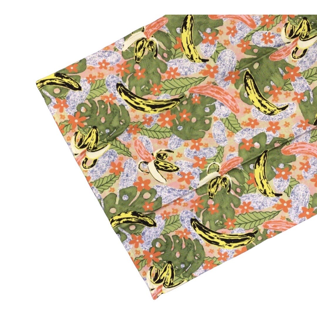 Banana tea towel features a fun illustration of bananas on green leaves with orange flowers. 