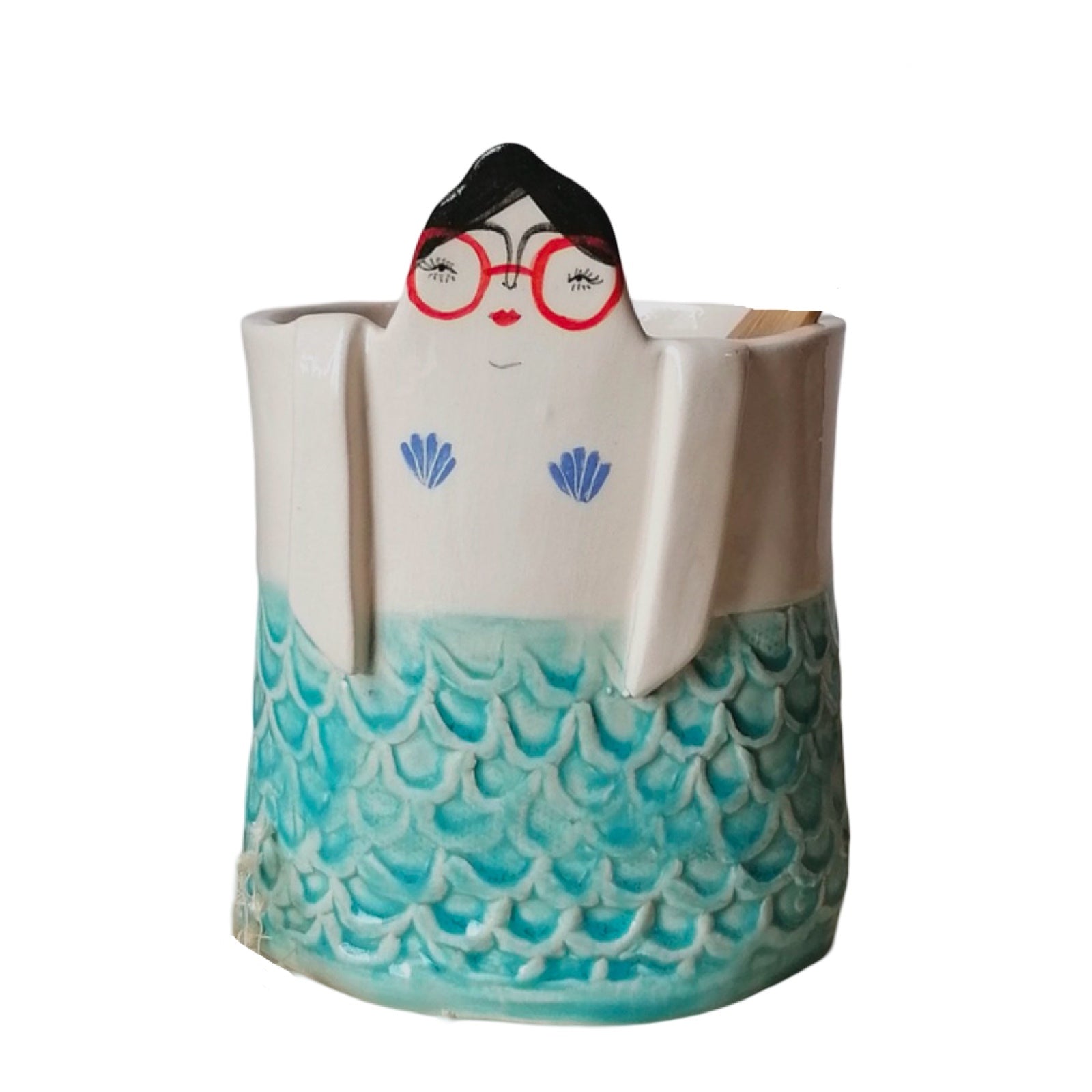 A handmade ceramic pot with teal mermaid scales and a lady's head with dark hair and red glasses