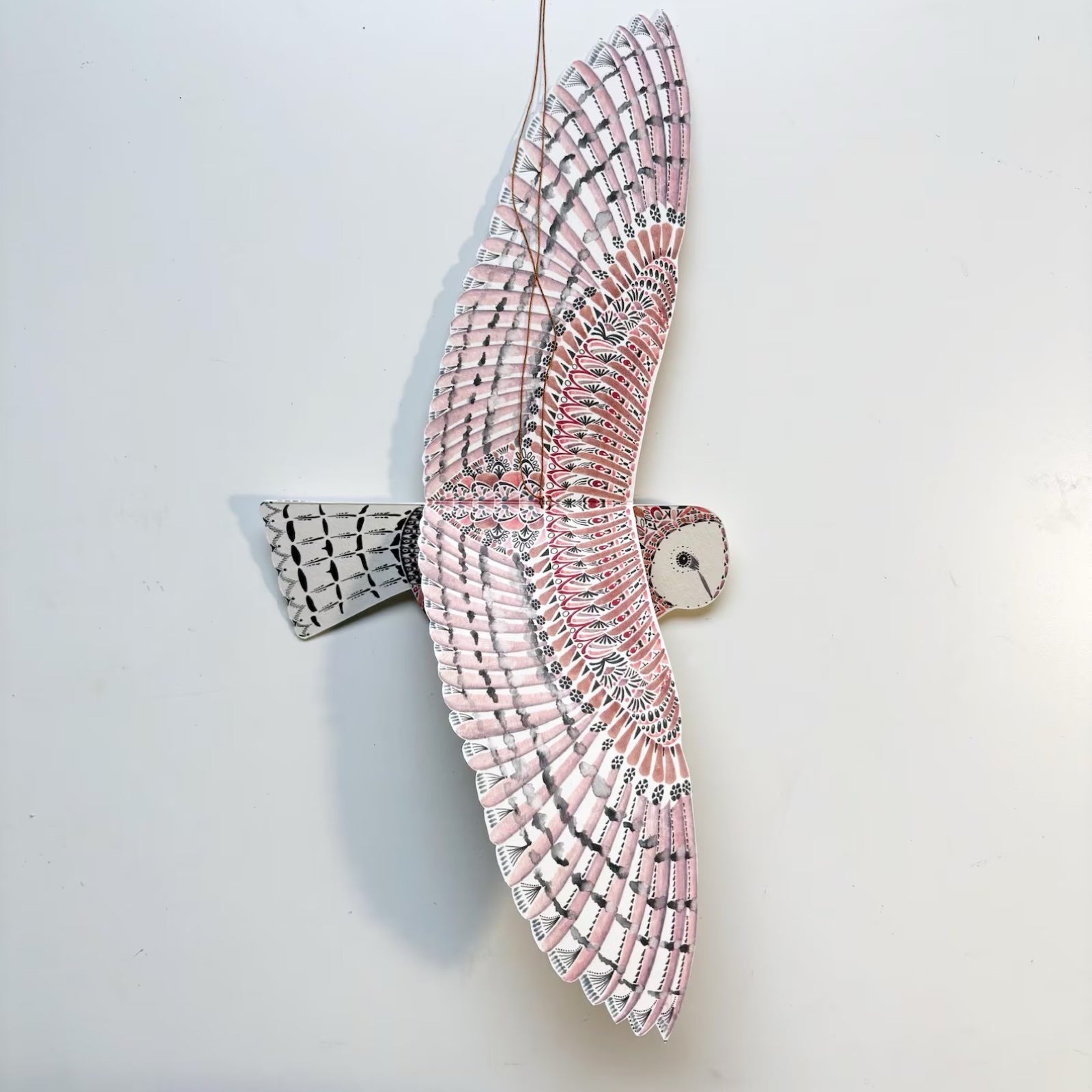 Decorative wall art of a bird with pink and gray wings on a white background.