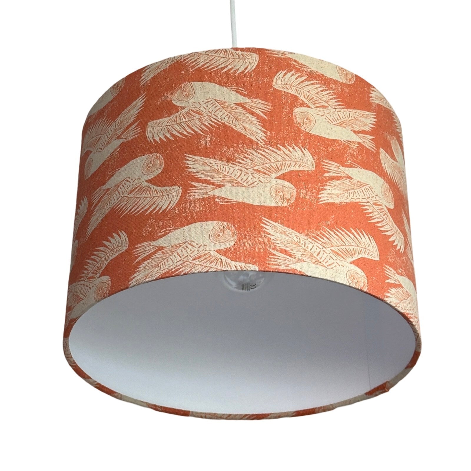 Drum lampshade covered in coral fabric with cream flying barn owls