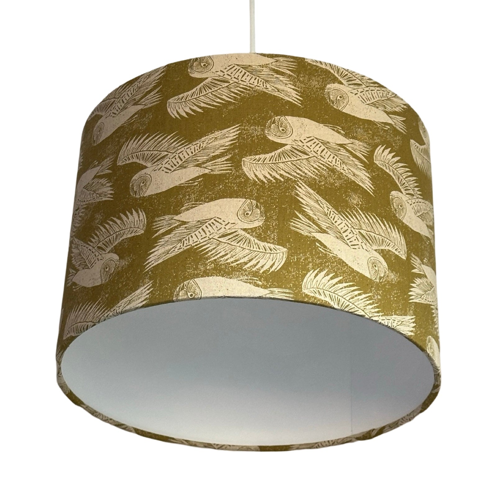 Drum lampshade covered in olive green-coloured cotton/linen blend fabric with cream flying barn owls.