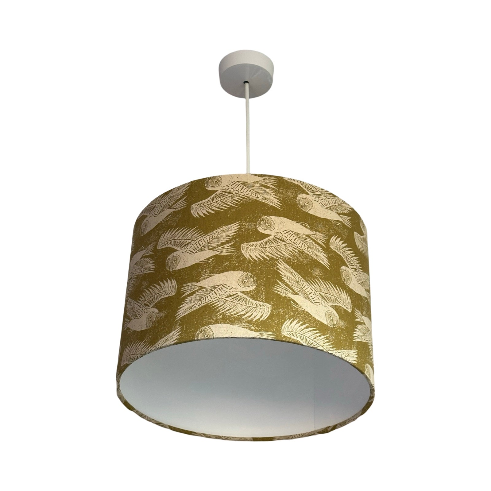 Drum lampshade covered in olive green-coloured cotton/linen blend fabric with cream flying barn owls.