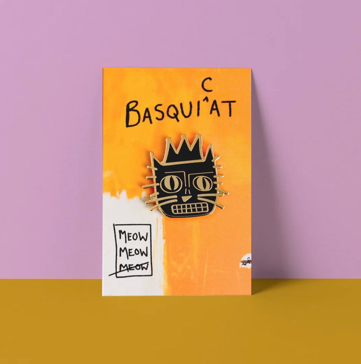 Cat illustration pin badge on yellow card on a purple background.