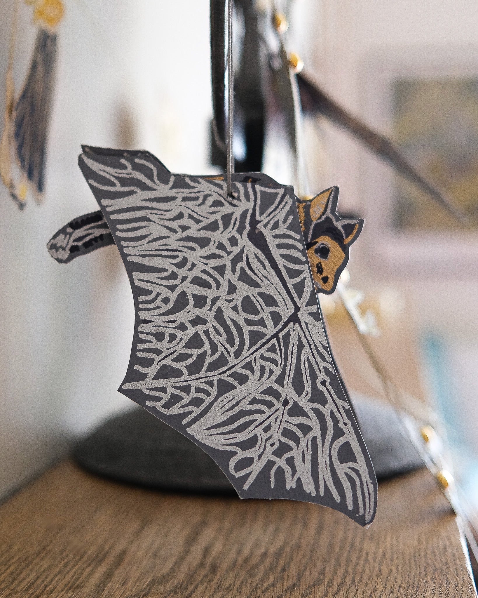 Decorative wall hanging with bat design on a wooden surface.