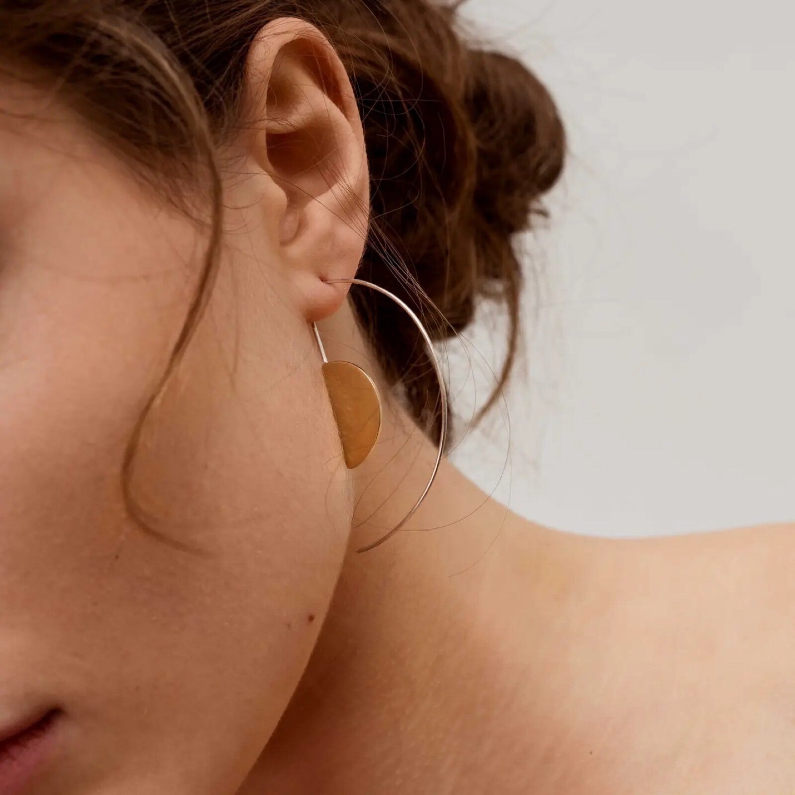 Handmade sterling silver hoop earrings in the style of Bauhaus. These elegant earrings have a central half circle in brass.