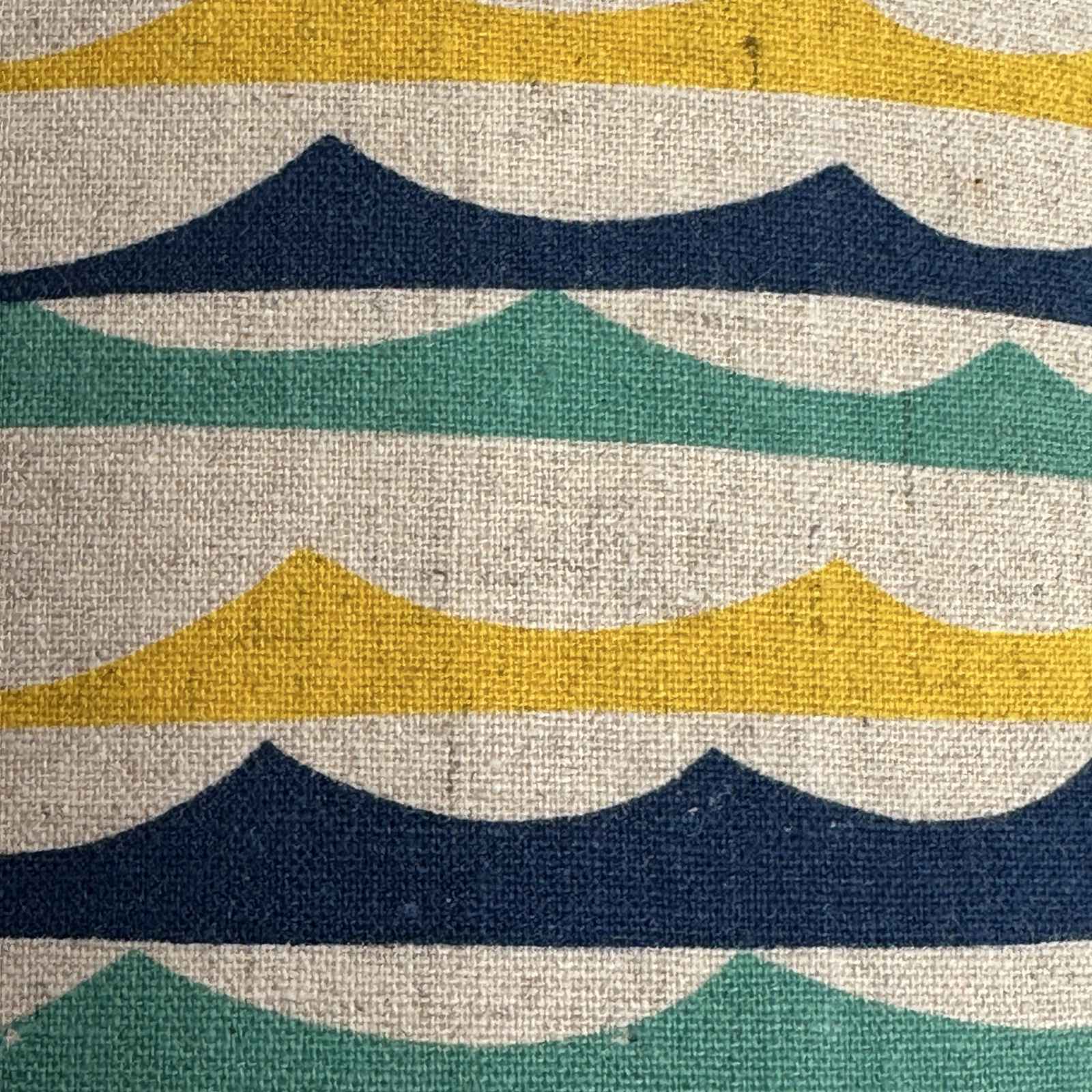 Colourful striped green, blue and yellow beach wave lampshade on a white background.