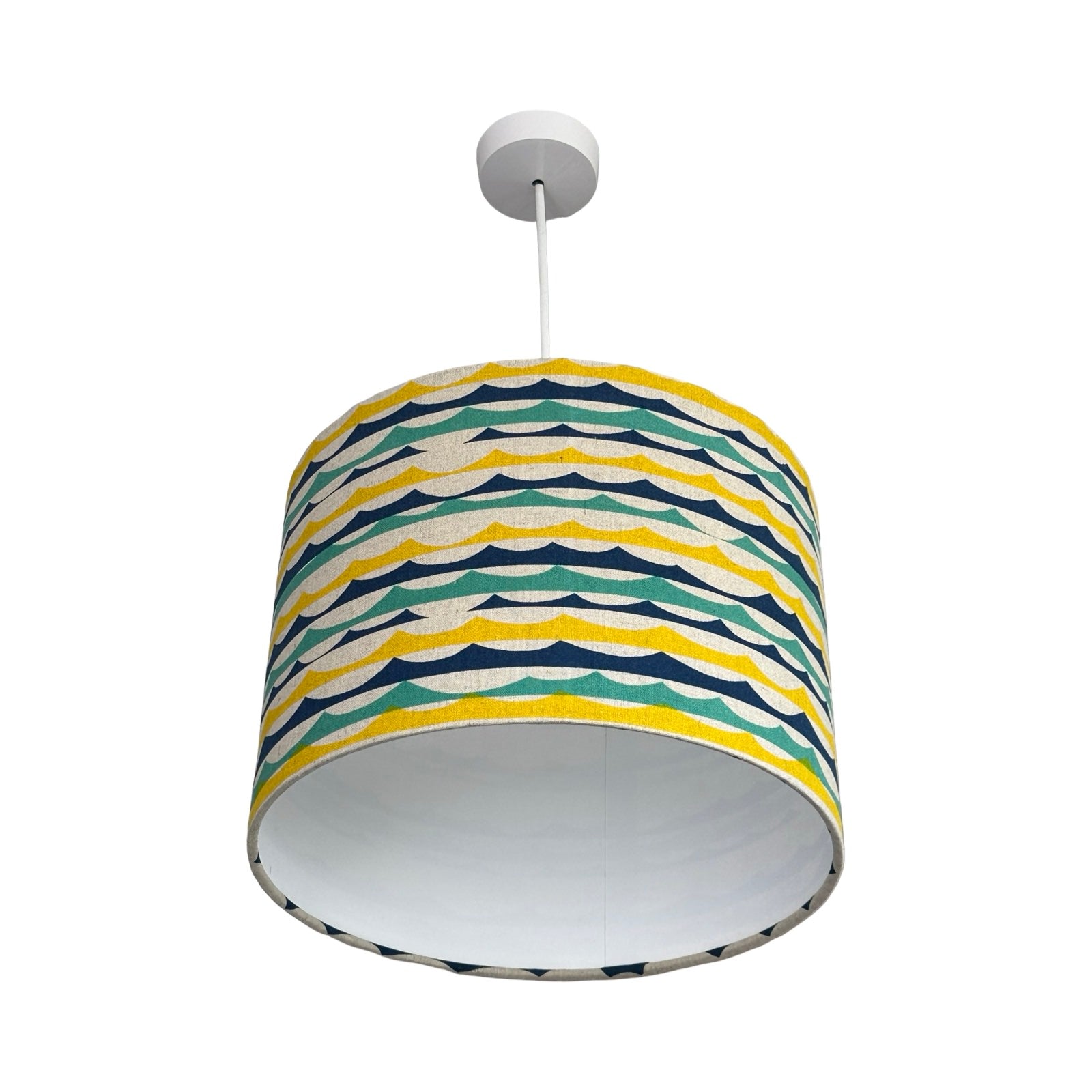 Colourful striped green, blue and yellow beach wave lampshade on a white background.