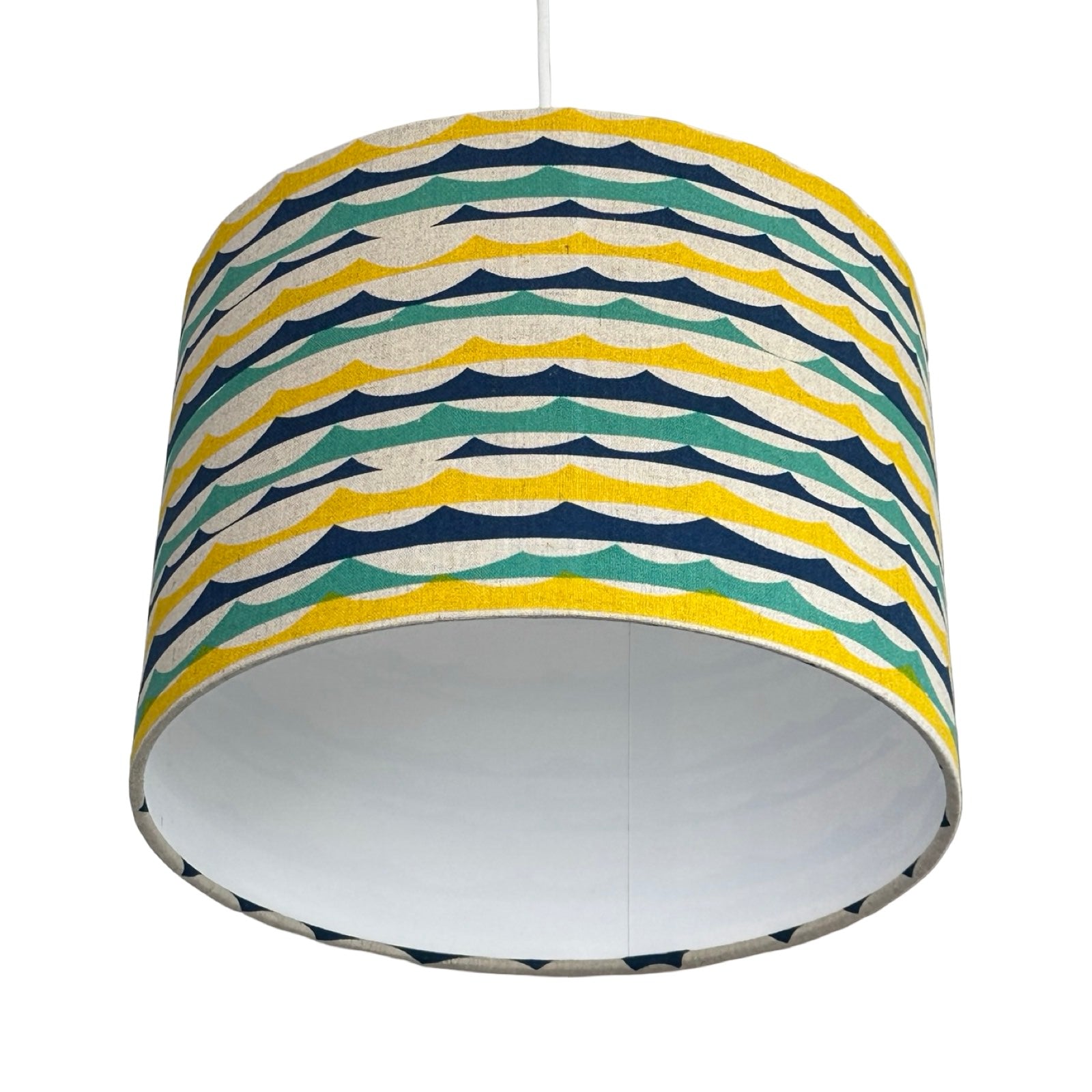 Colourful striped green, blue and yellow beach wave lampshade on a white background.