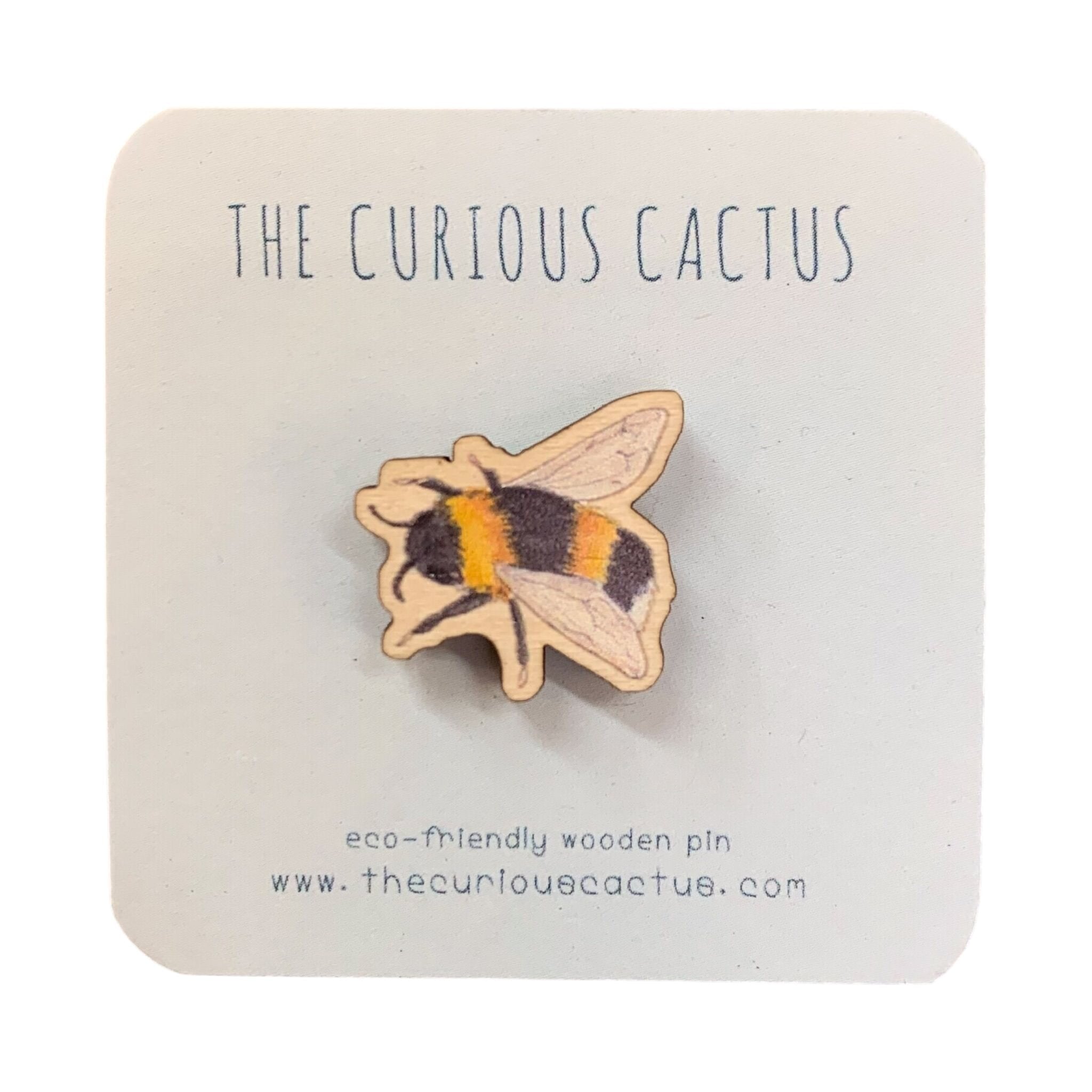 Mini wooden bee-shaped pin badge of a bee in flight on a light blue backing card.