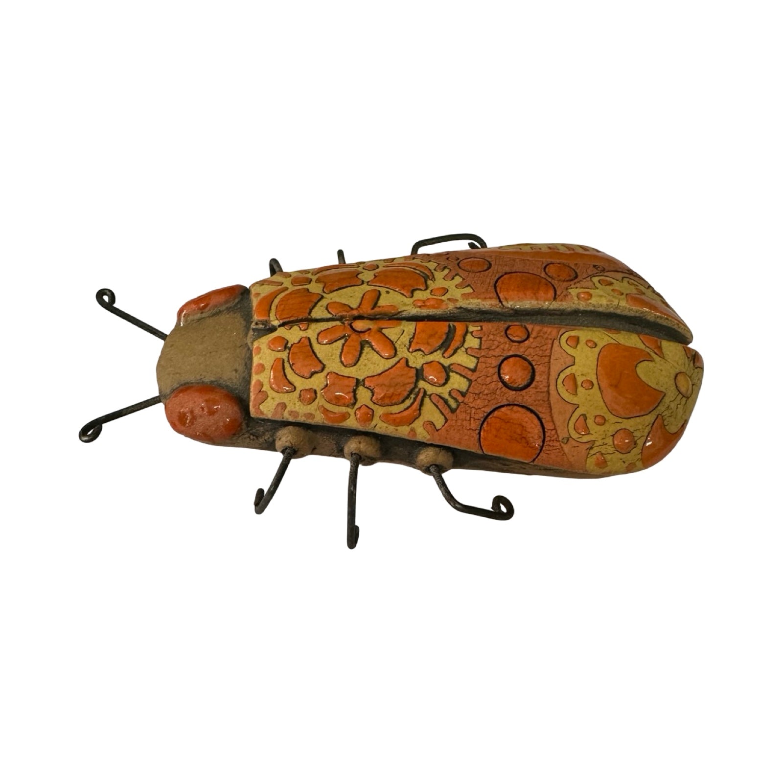 A long ceramic beetle in orange with orange and yellow flowers and orange spots and wire legs.